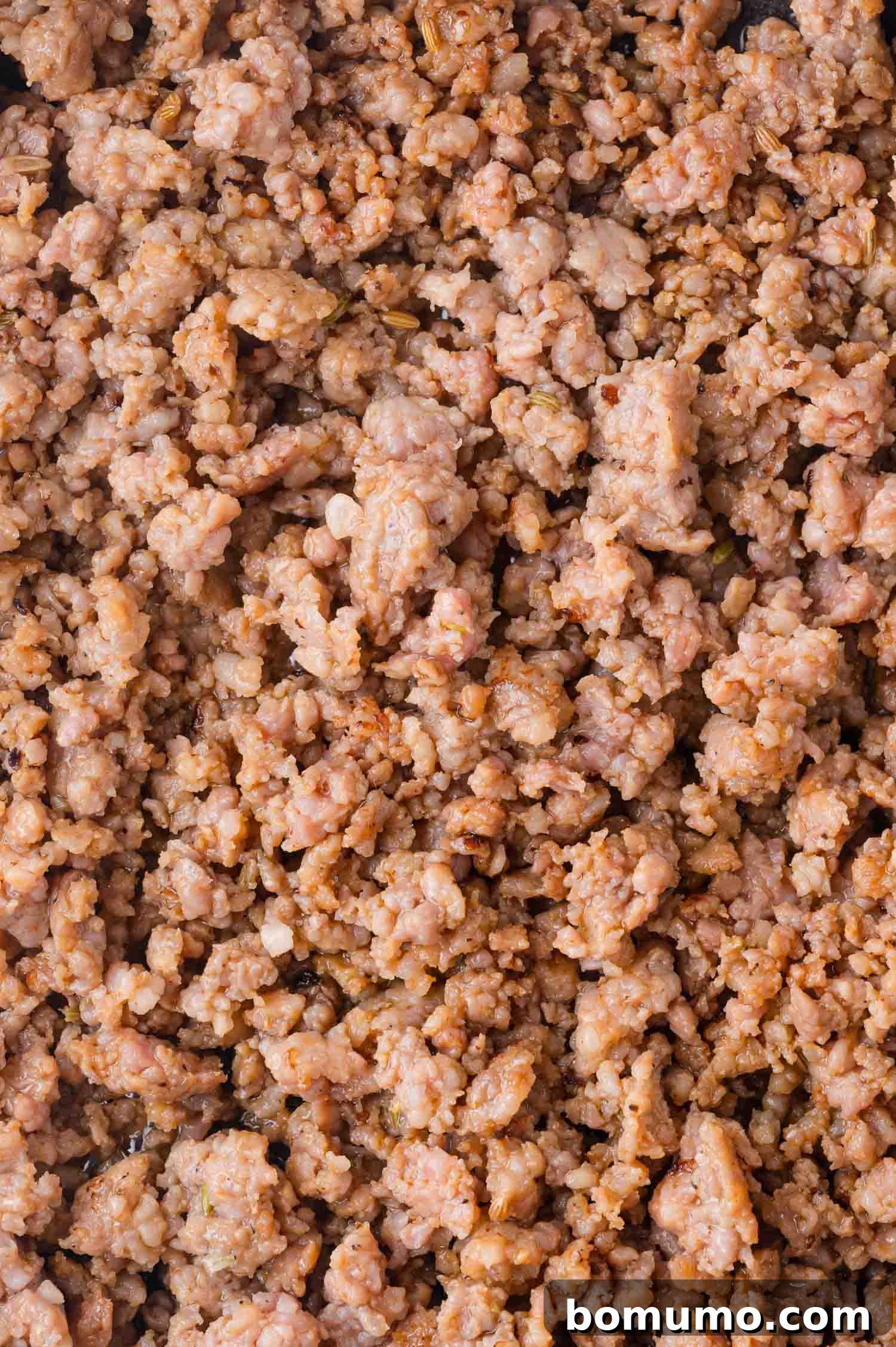 Protein-Packed Egg White Bites 5 Cooked ground sausage crumbles, light brown in color, spread out in an even layer in a skillet, indicating it's perfectly browned.