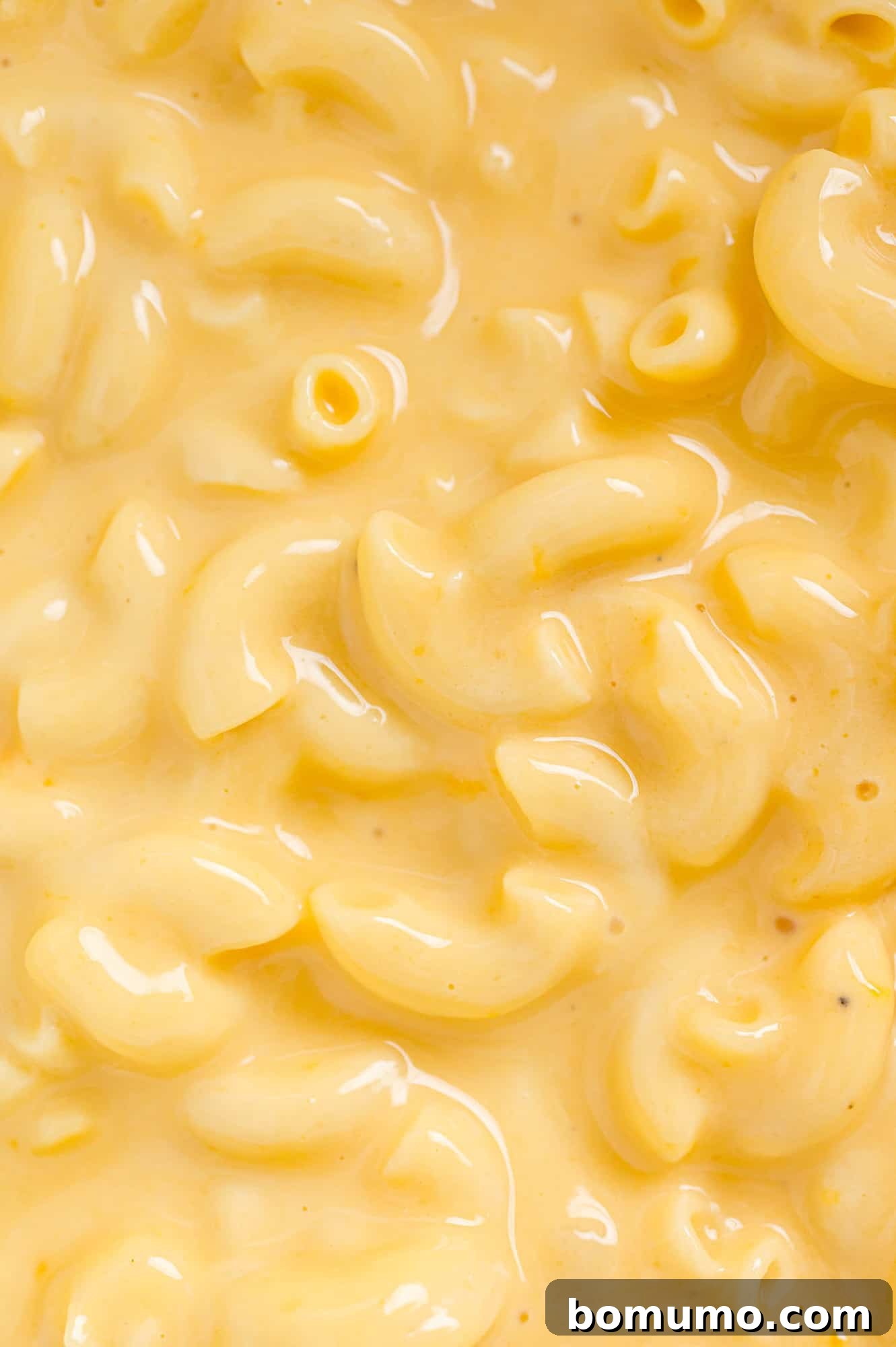 A stunning close-up shot of a full crockpot of creamy macaroni and cheese, filling the entire frame, highlighting its irresistible golden color, rich texture, and steaming warmth.