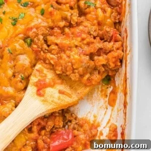 Stuffed pepper casserole being scooped out with a wooden spoon, showcasing the delicious blend of ingredients.
