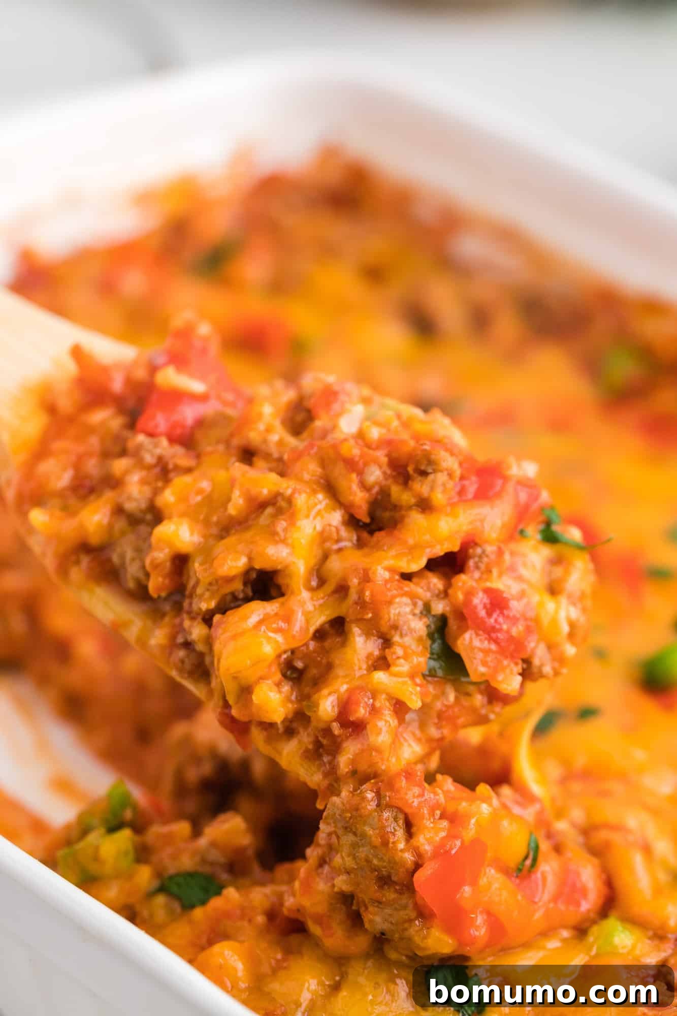 A serving spoon gracefully scooping a portion of the wholesome stuffed pepper casserole, highlighting its rich texture and ingredients.