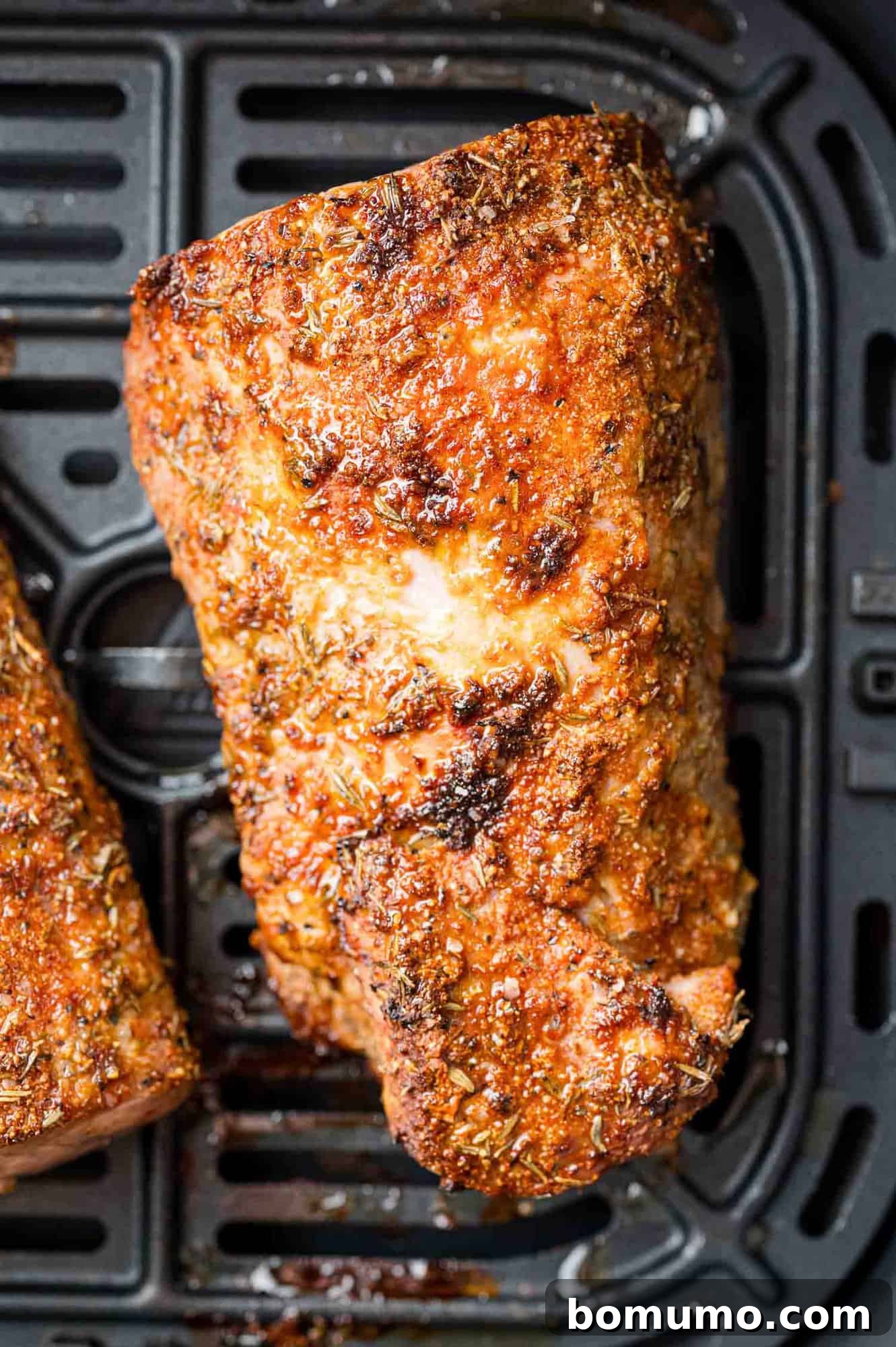 Perfectly cooked and golden-brown pork tenderloin resting inside the air fryer basket after cooking.