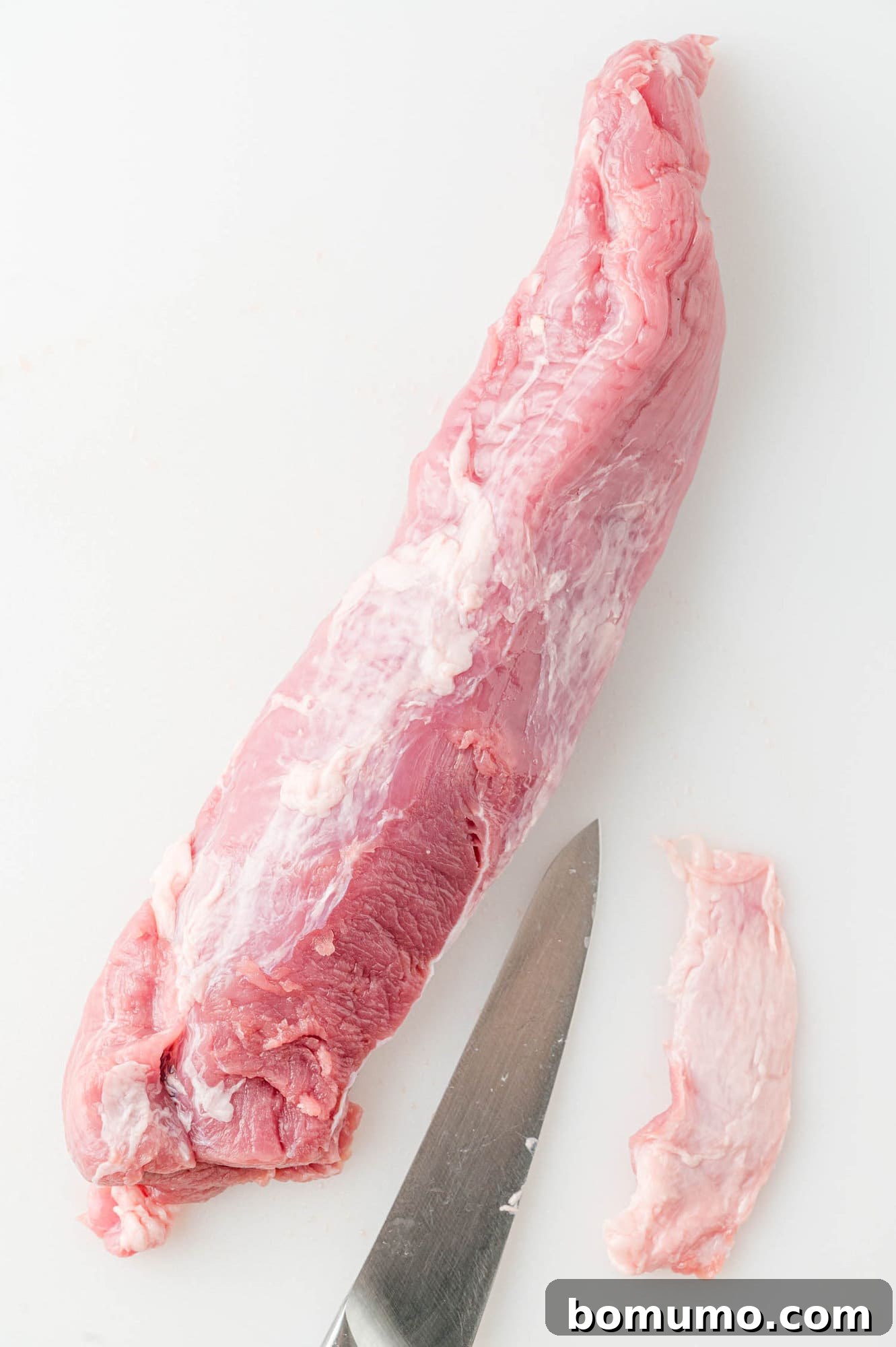 The pork tenderloin after the silver skin has been cleanly and completely removed, ready for seasoning.