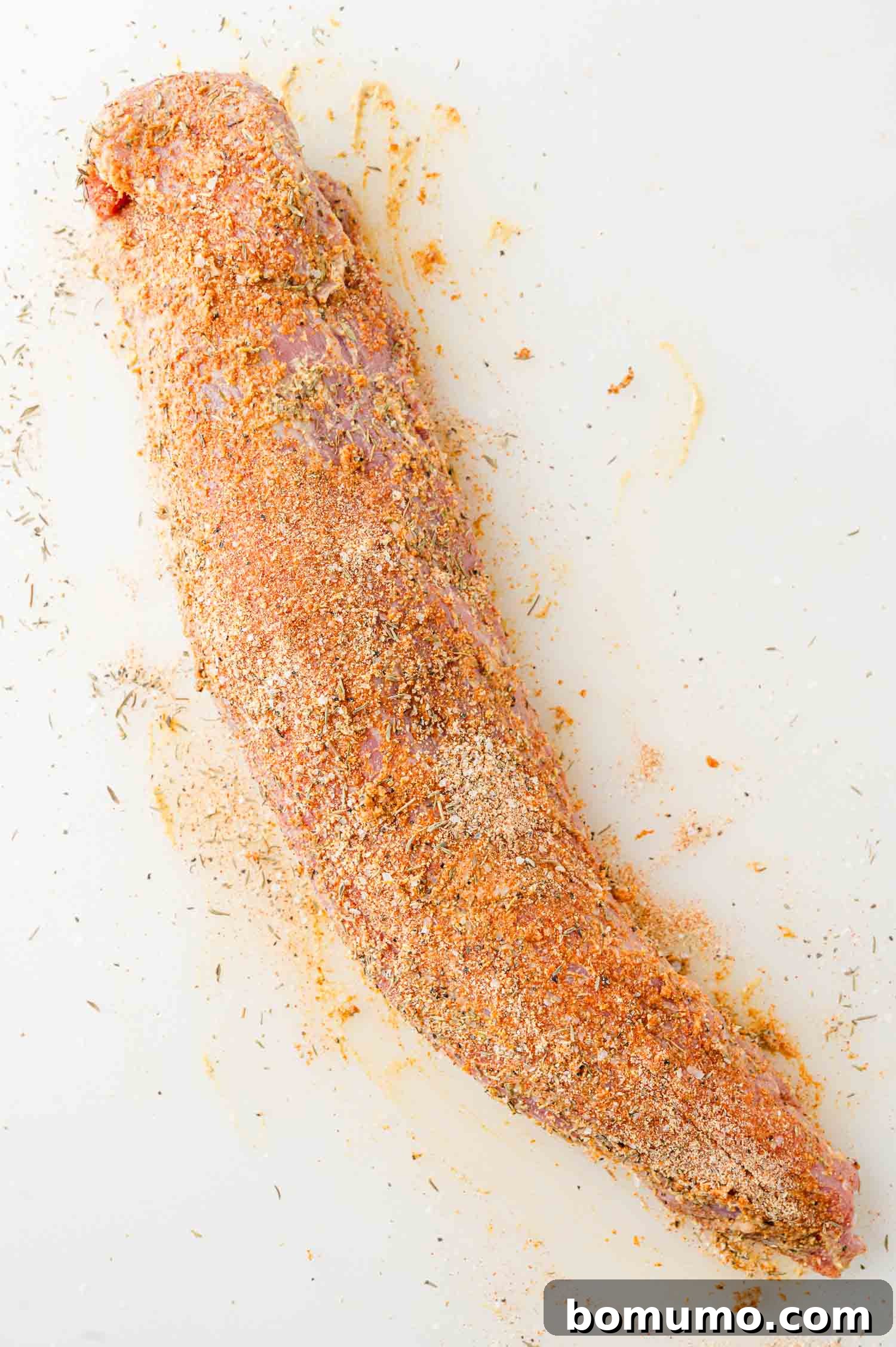 Raw pork tenderloin, beautifully coated with a robust spice rub, showcasing its readiness for cooking.