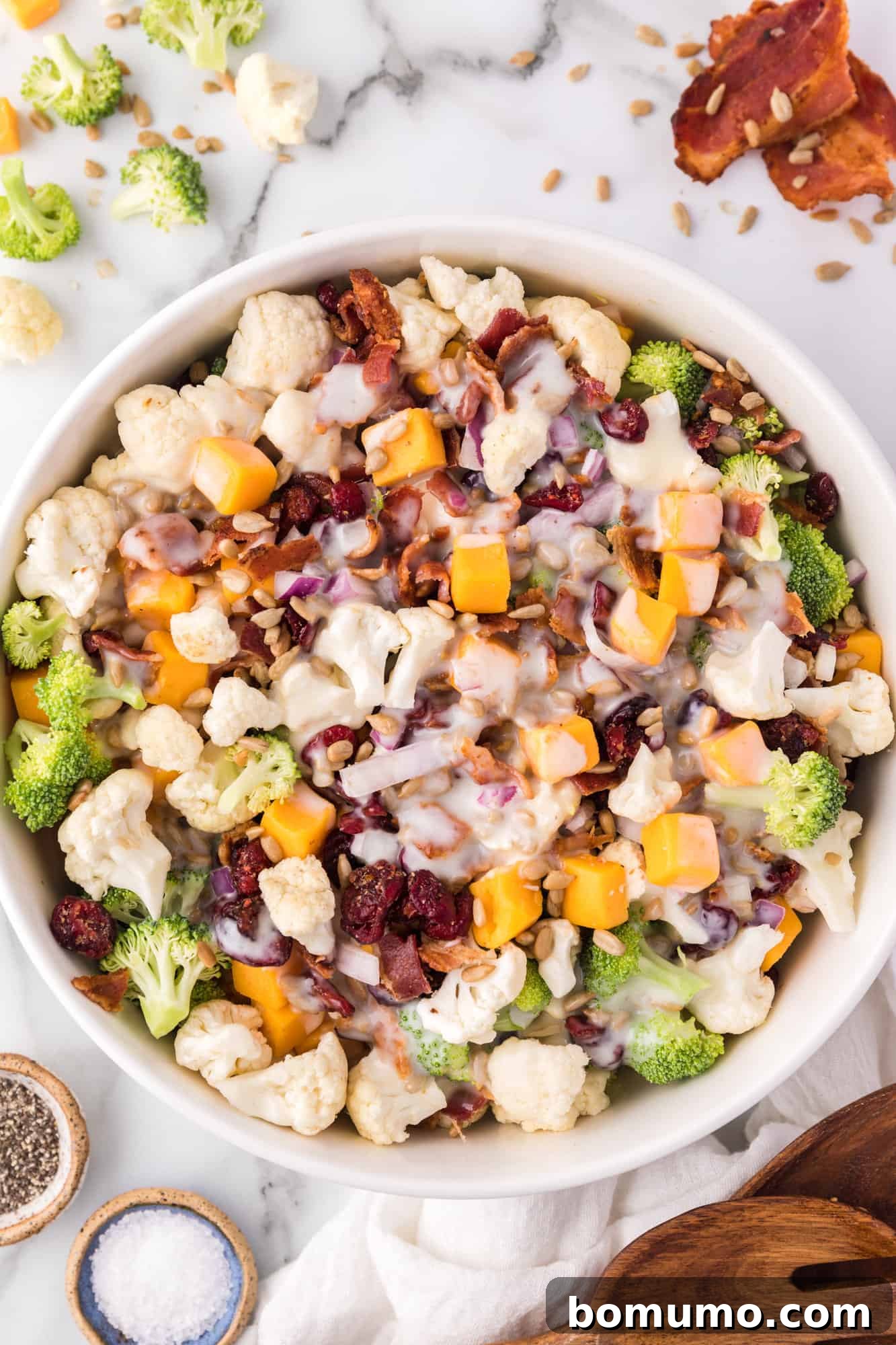 Overhead view of a beautifully presented broccoli cauliflower salad in a large bowl, ready to be served.