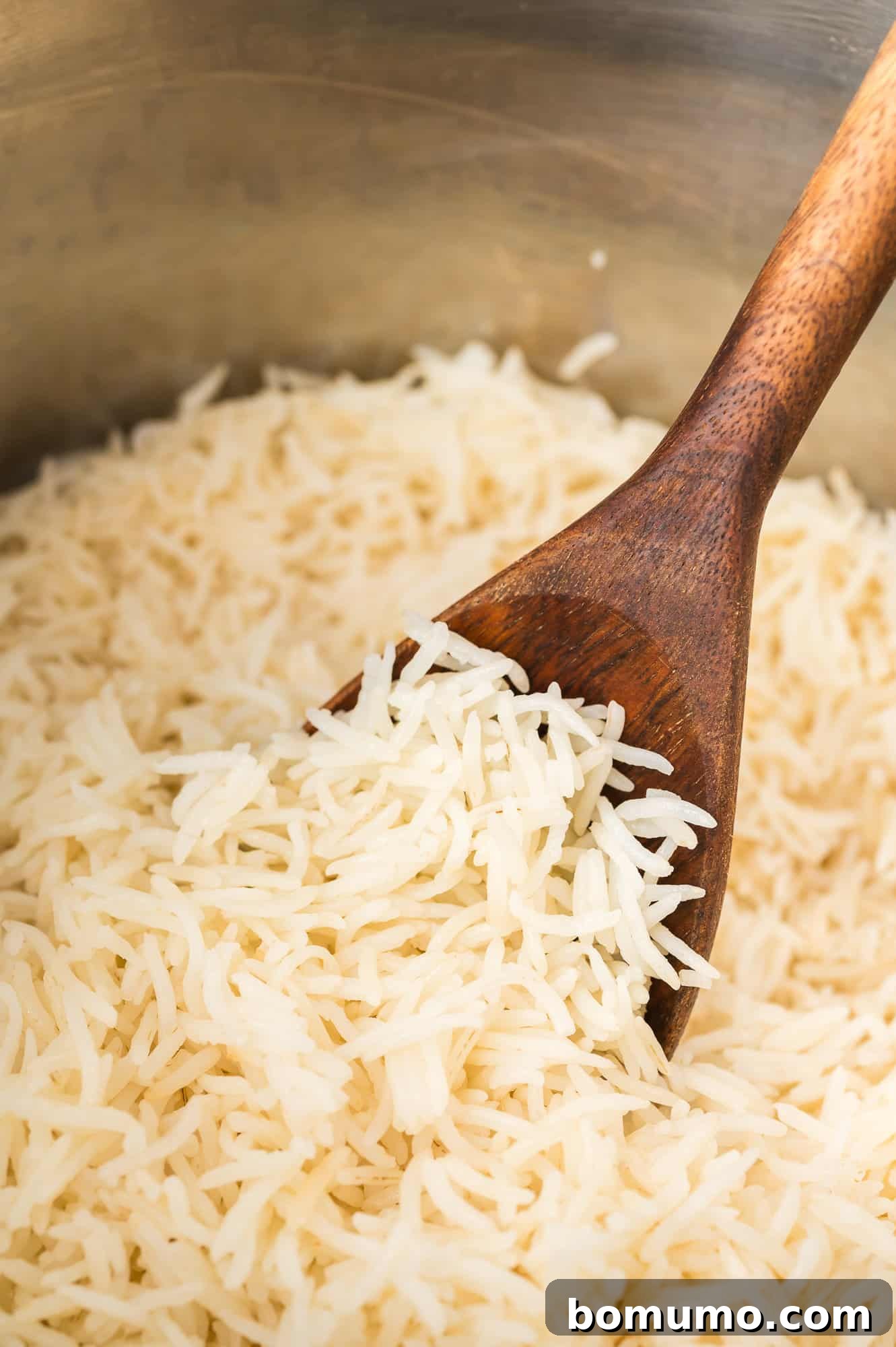 Instant pot basmati rice, perfectly cooked and fluffy, still in the Instant Pot and being scooped onto a wooden spoon.
