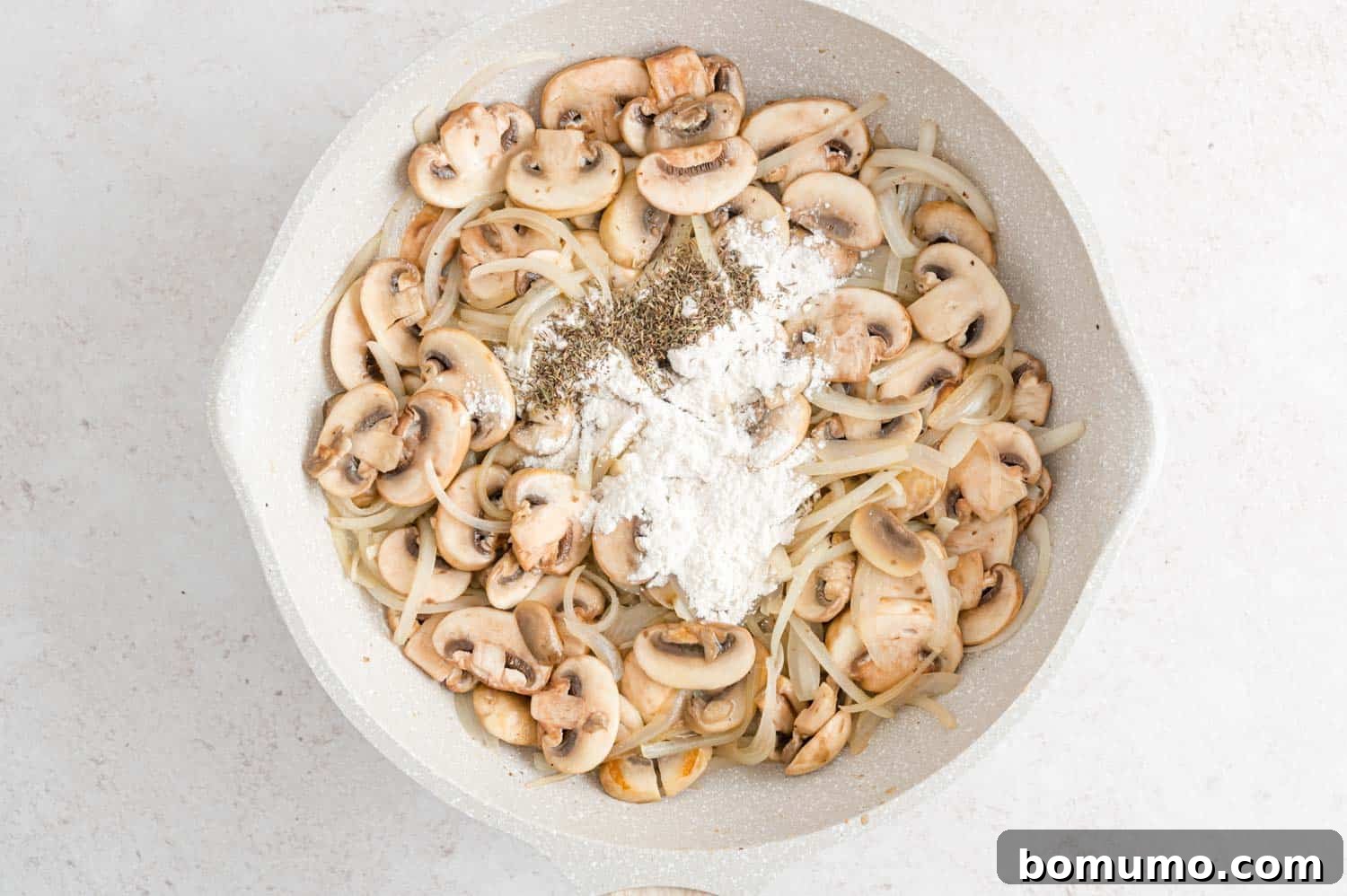 Velvety Chicken Stroganoff 8 Mushrooms and onions lightly dusted with flour in the skillet.