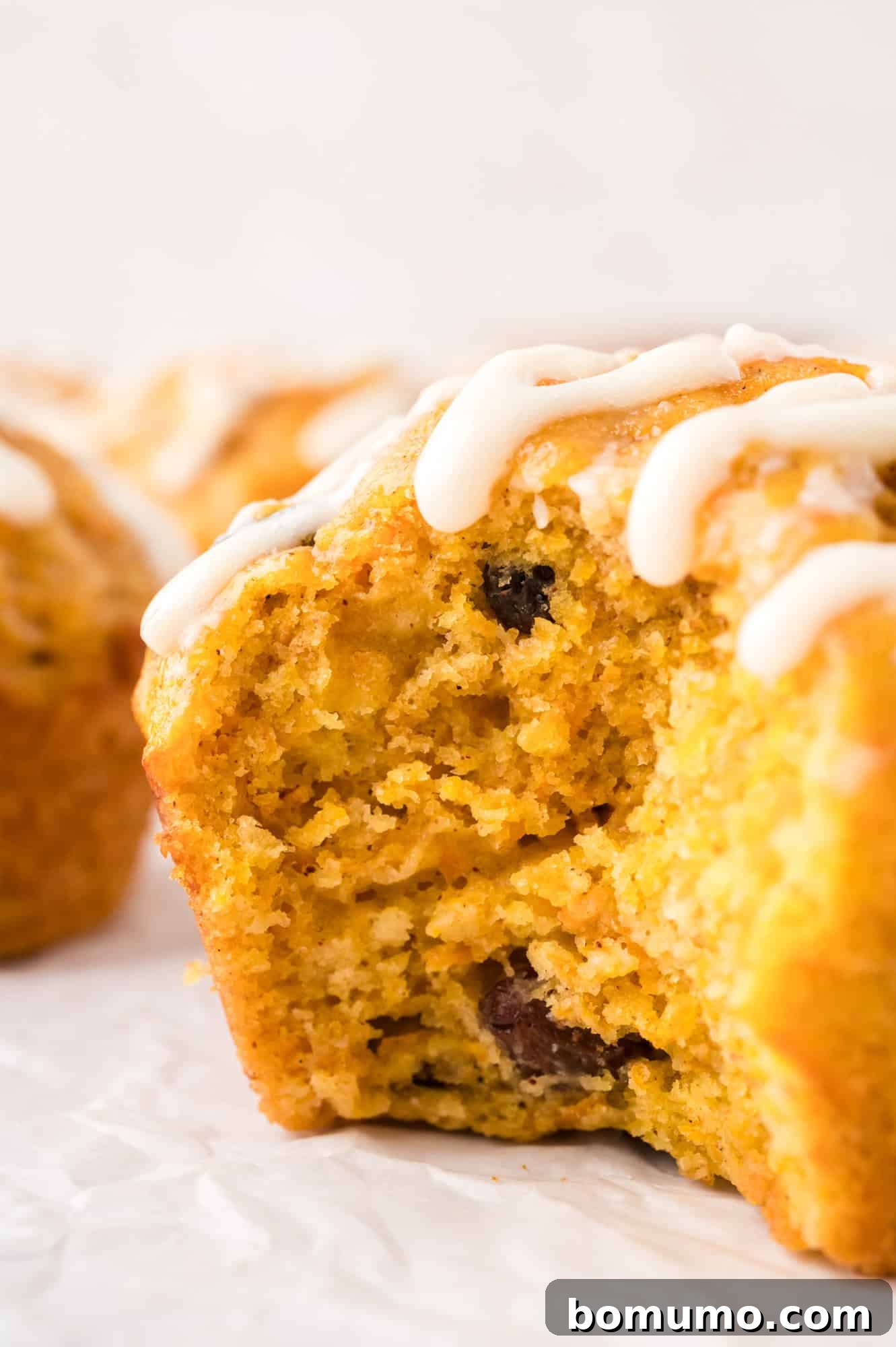 Carrot cake muffin with a large bite removed to show inside texture, highlighting its moist and tender crumb.