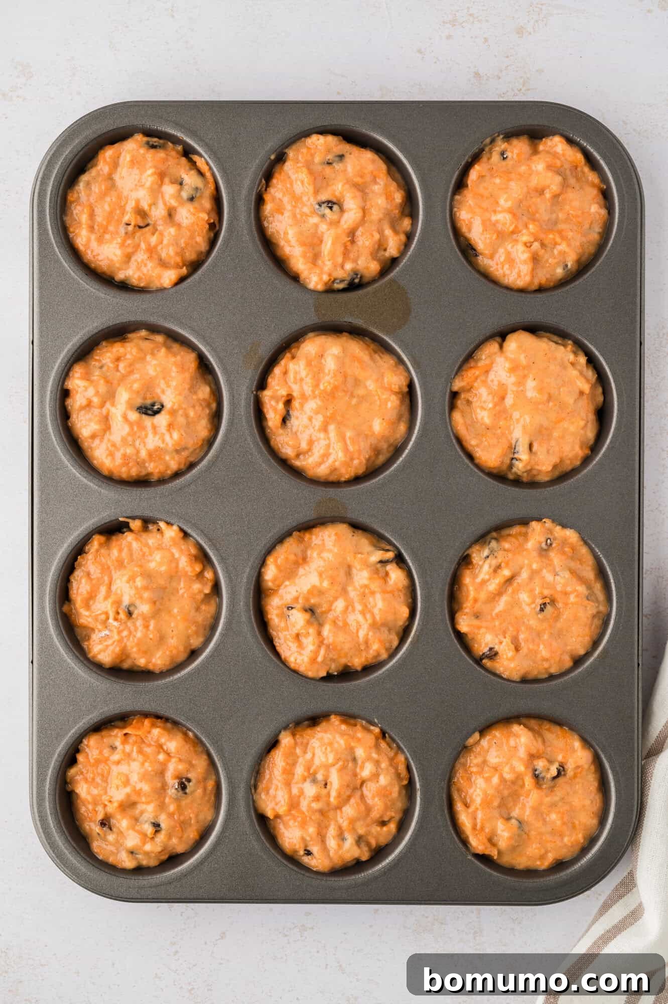 Muffins in a tin, before baking, showing the raw batter filling each cup.
