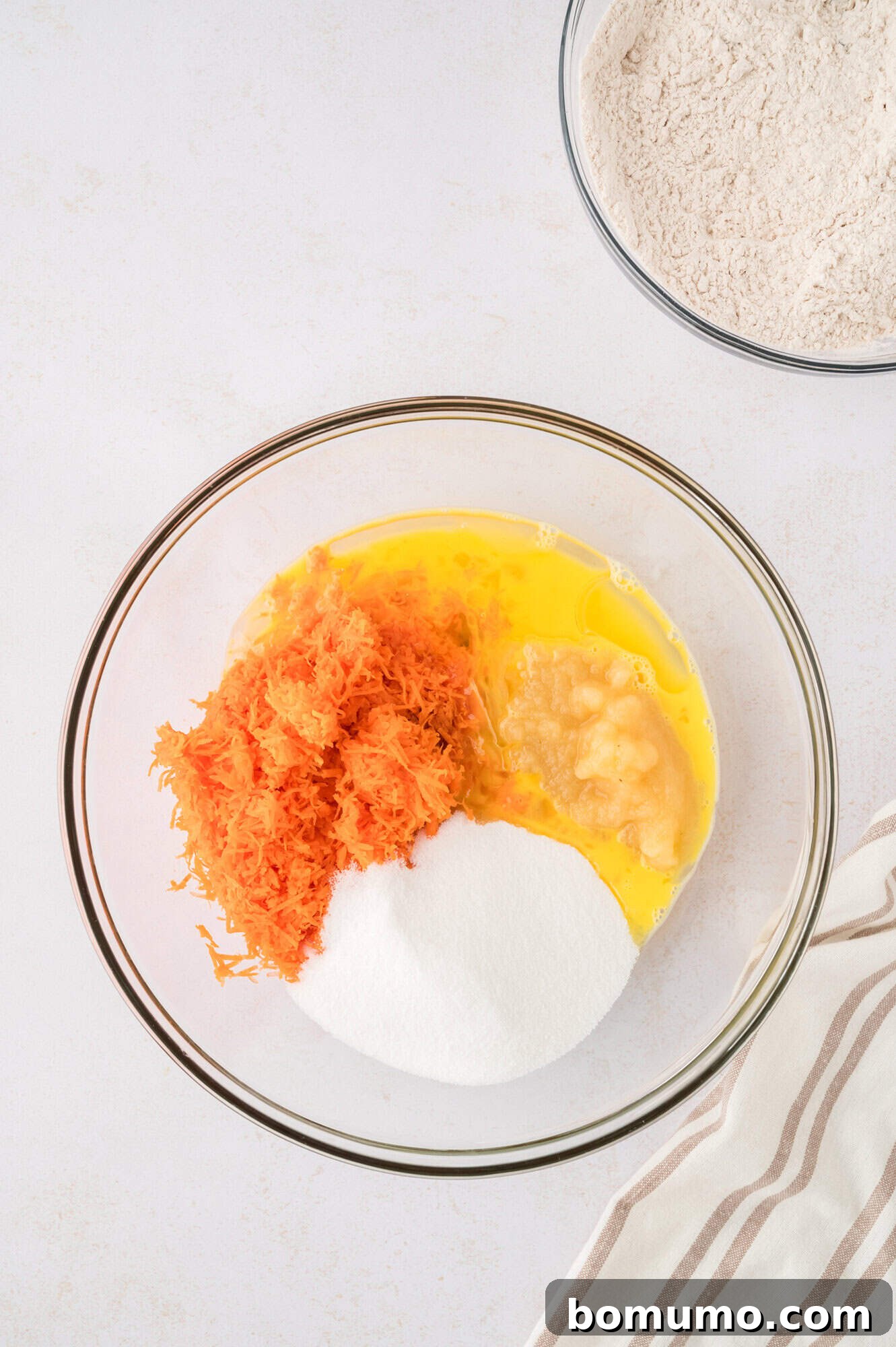 Wet ingredients (eggs, carrots, sugar, applesauce, oil, vanilla) all in the same bowl, not yet combined.