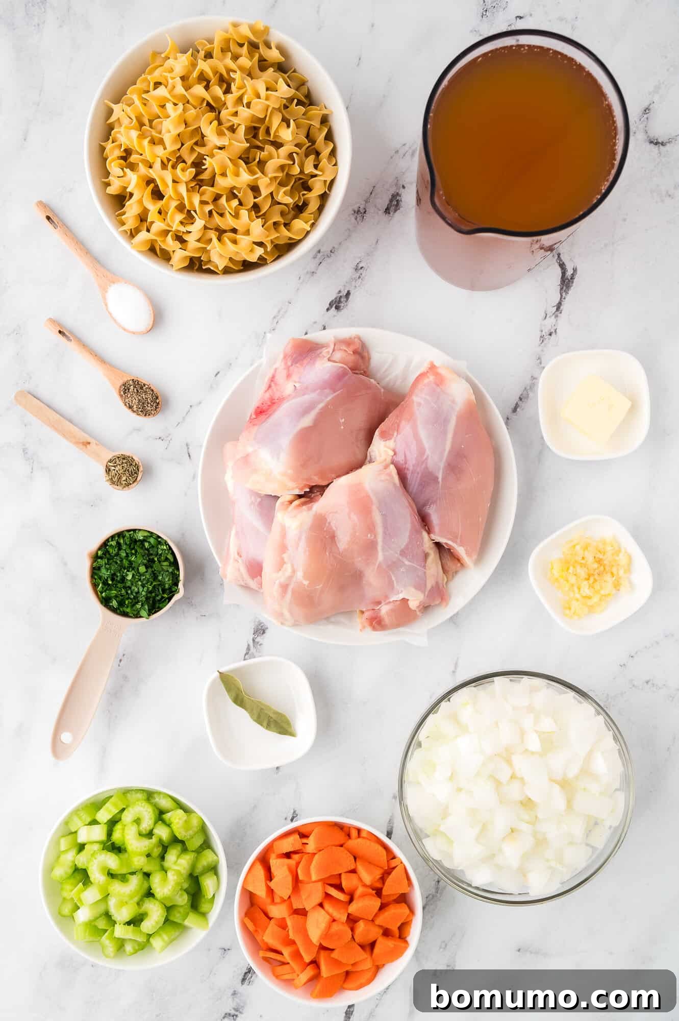 Fresh ingredients laid out for homemade chicken noodle soup: chicken, vegetables, and herbs, ready for preparation.