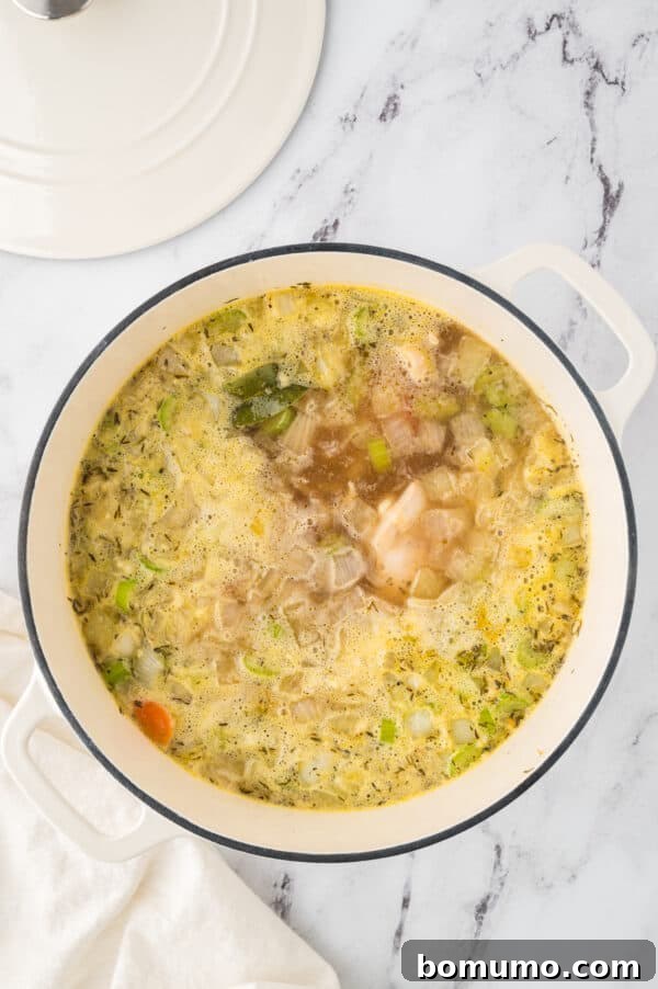 Chicken soup ingredients simmering gently in a large pot, allowing flavors to meld and chicken to cook through.