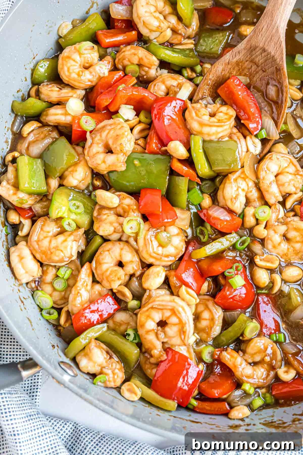Fiery Peanut Shrimp Delight 11 Fresh green onions and crunchy peanuts being added to the finished Kung Pao Shrimp in the frying pan, ready for serving.
