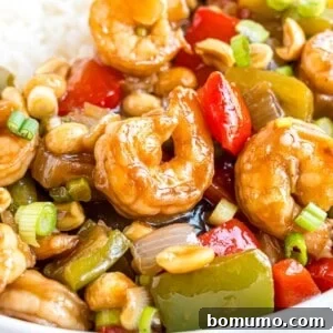 Kung Pao shrimp, shown with rice, garnished with green onions.