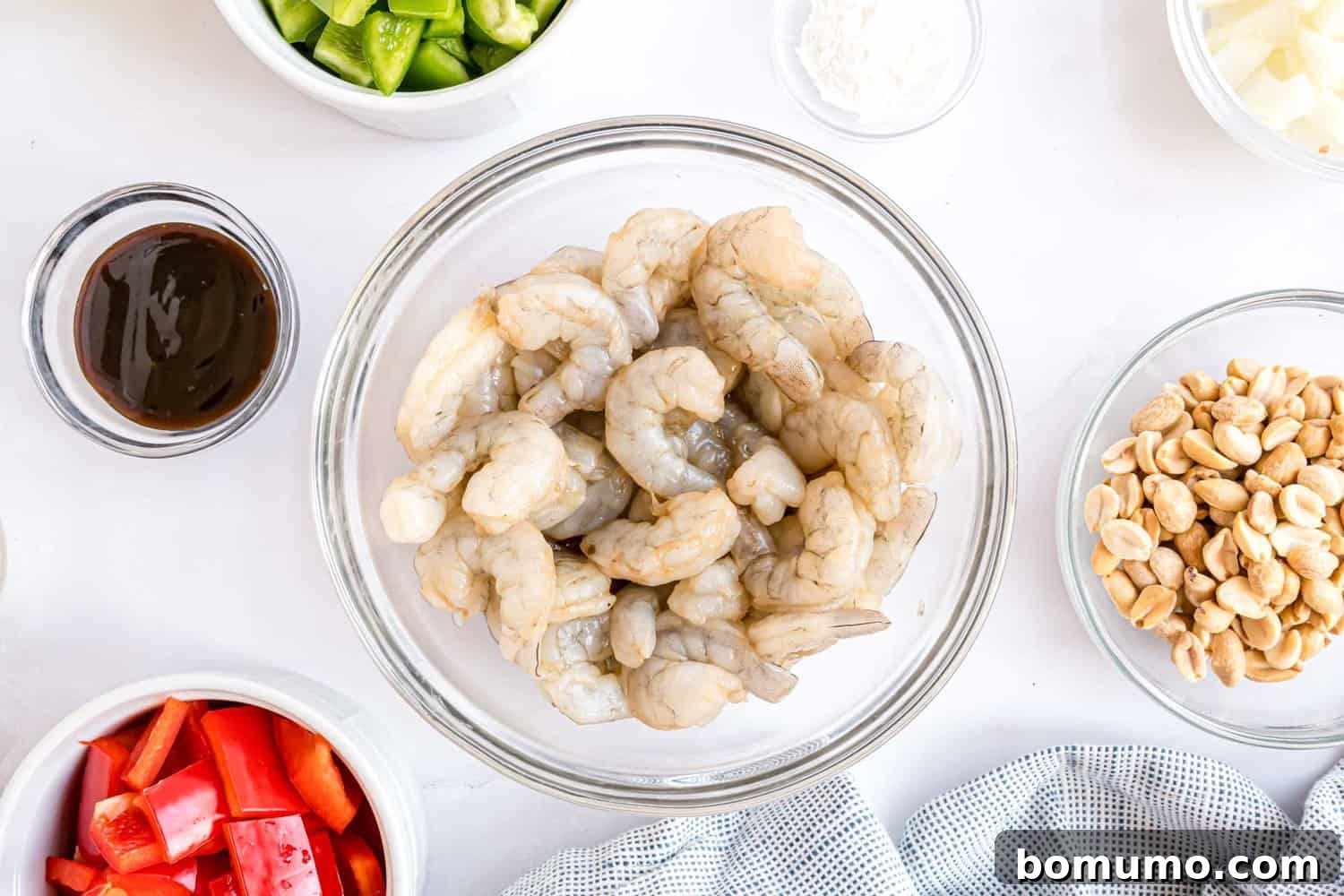 Fiery Peanut Shrimp Delight 6 Raw shrimp fully coated in a flavorful marinade, resting in a bowl, ready for cooking.