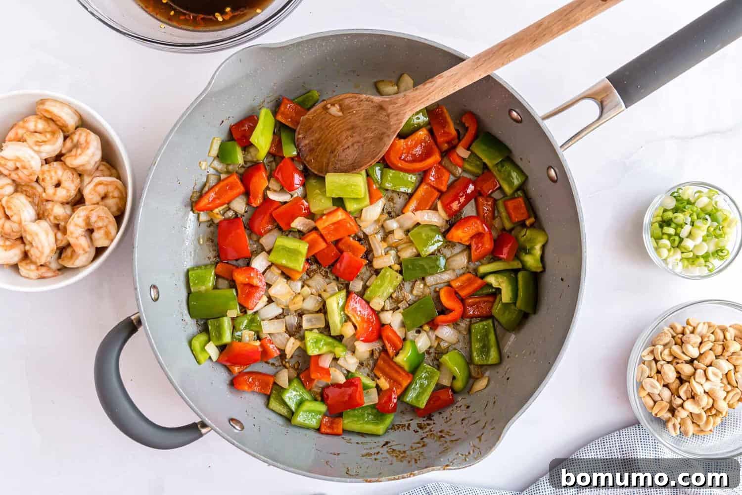 Fiery Peanut Shrimp Delight 9 Fresh vegetables being actively stir-fried in a large, hot frying pan, creating a vibrant and aromatic scene.