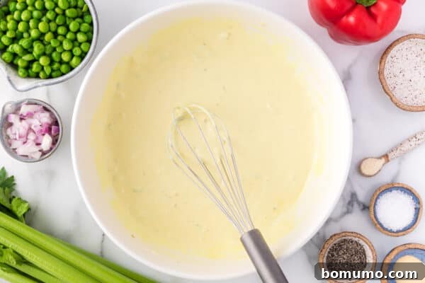 Macaroni salad dressing being whisked in a bowl, showing its creamy texture.