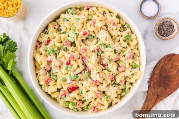 Overhead view of a finished chicken macaroni salad in a bowl, garnished and ready to serve.