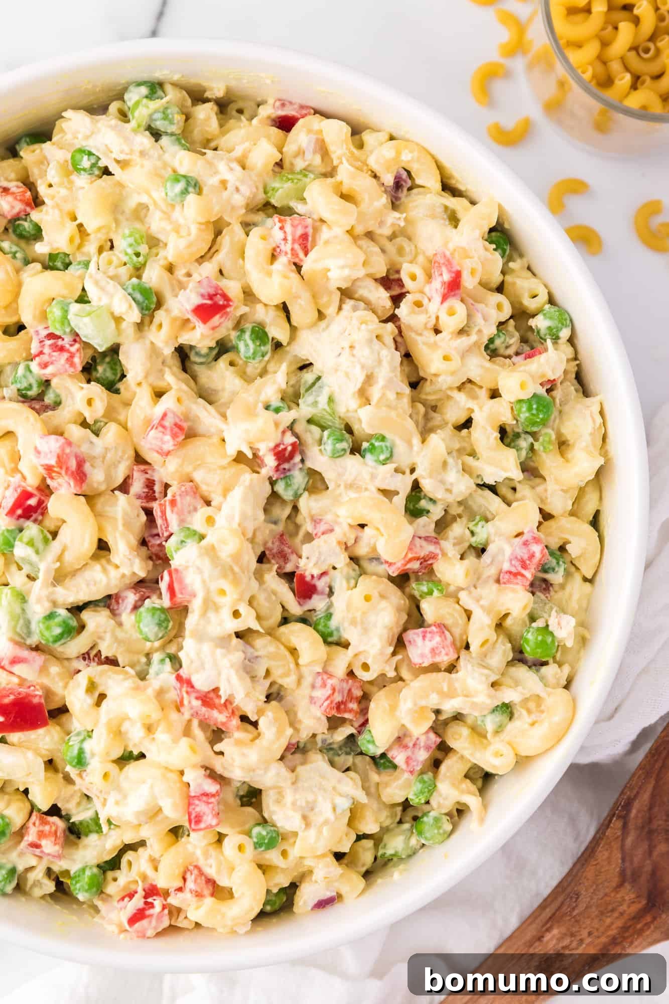 Overhead view of chicken macaroni salad in a large bowl with a serving spoon.