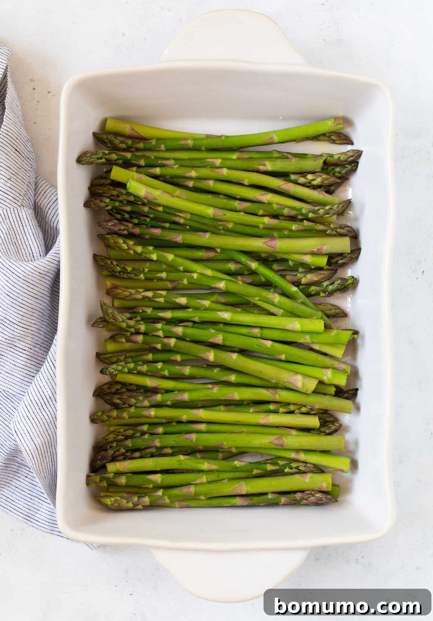 Creamy Asparagus Bake 6 Uncooked asparagus spears arranged neatly in a greased 9x13 inch baking dish, ready for sauce.
