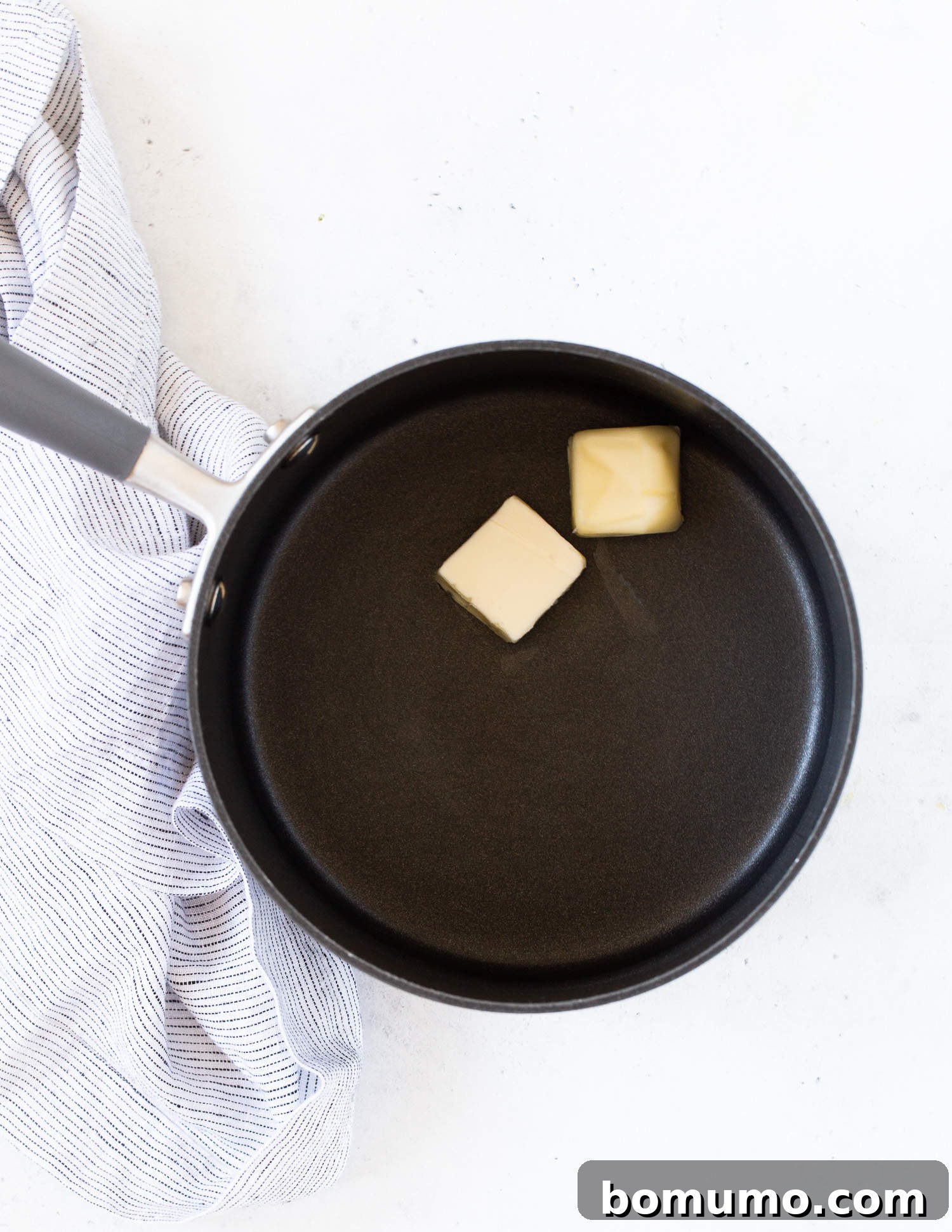 Creamy Asparagus Bake 7 Unmelted butter cubes in a black saucepan, ready to be melted for the cheese sauce.