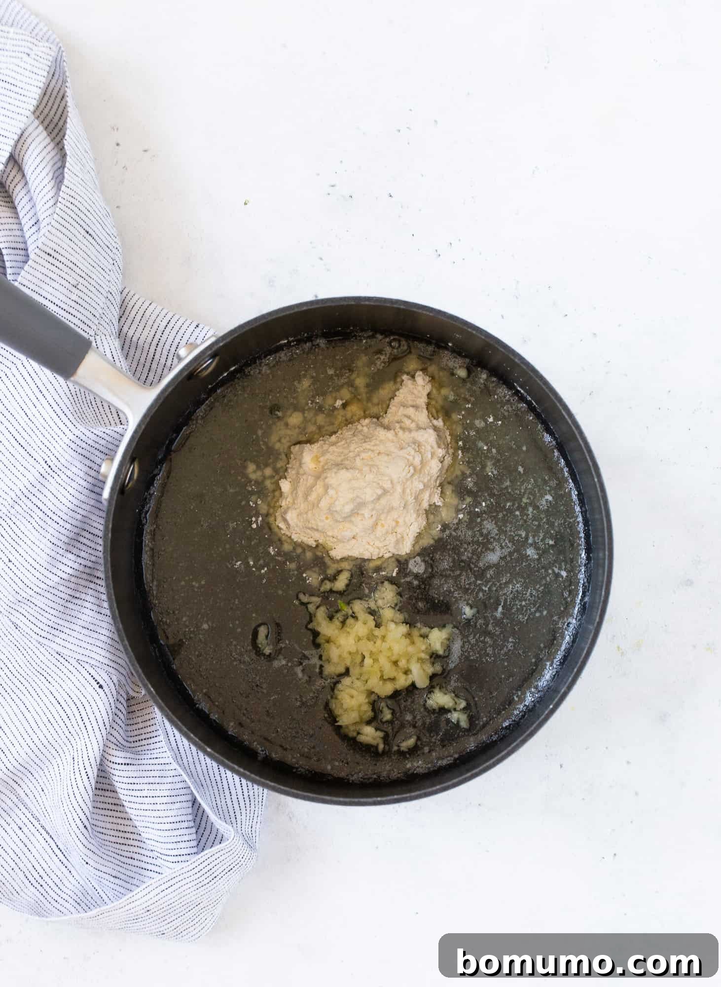 Creamy Asparagus Bake 8 All-purpose flour and minced garlic added to melted butter in a saucepan, forming a roux.