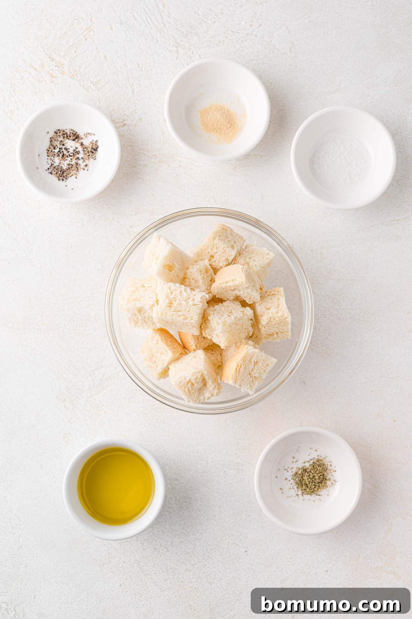 All the necessary ingredients laid out for making air fryer croutons, including cubed bread, olive oil, and seasonings.
