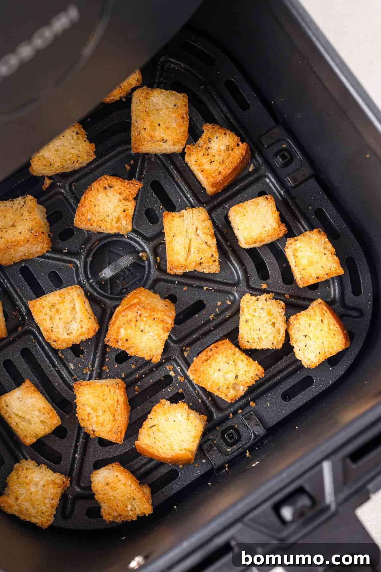 Perfectly golden-brown and crispy croutons after cooking, still in the air fryer basket.