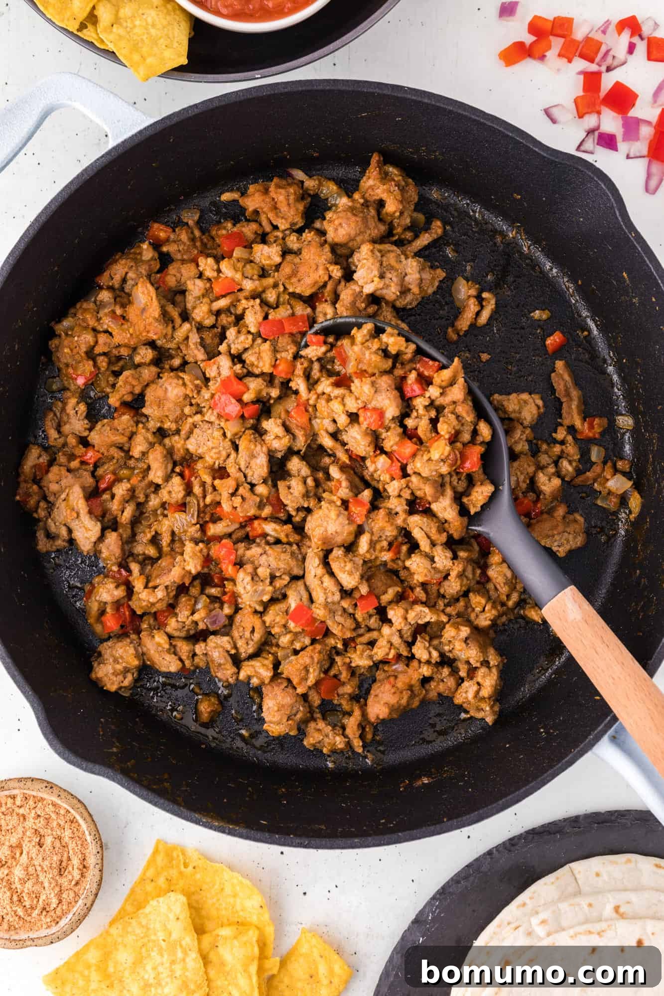 Overhead view of turkey taco meat in a cast iron skillet with a spoon.