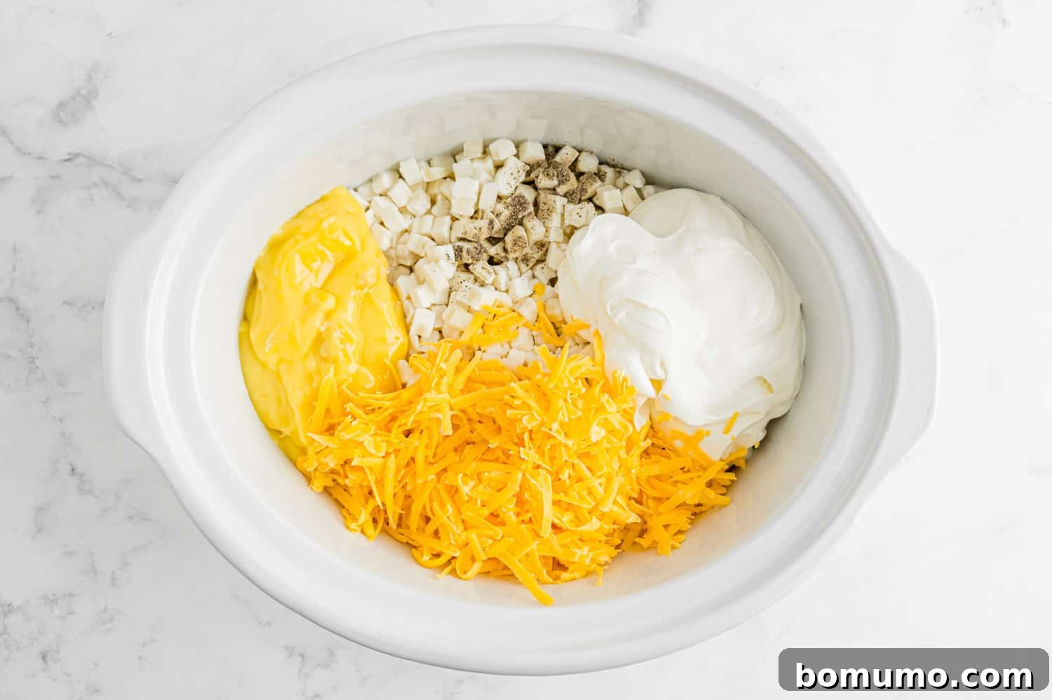 Ingredients, not mixed together, in a slow cooker.