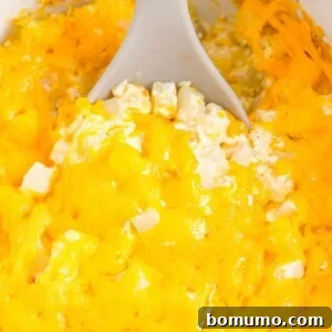 Spoon scooping out cheesy potatoes in a slow cooker.