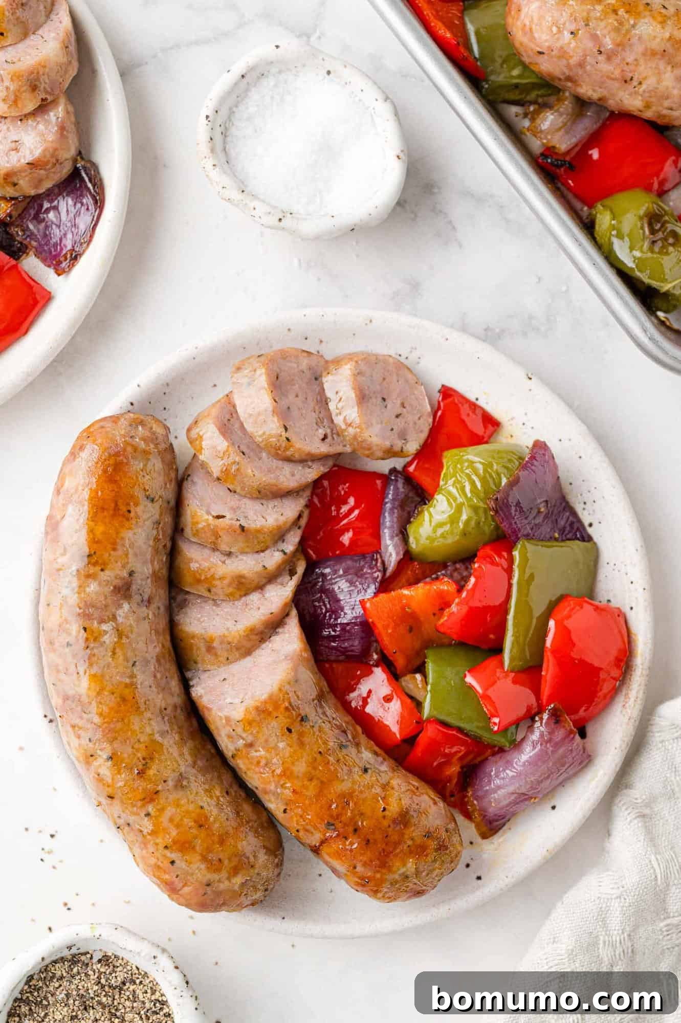 Plated baked Italian sausage served with vibrant roasted bell peppers and onions, a perfect, hearty meal.