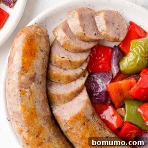 Baked Italian sausage with peppers and onions, partially sliced.
