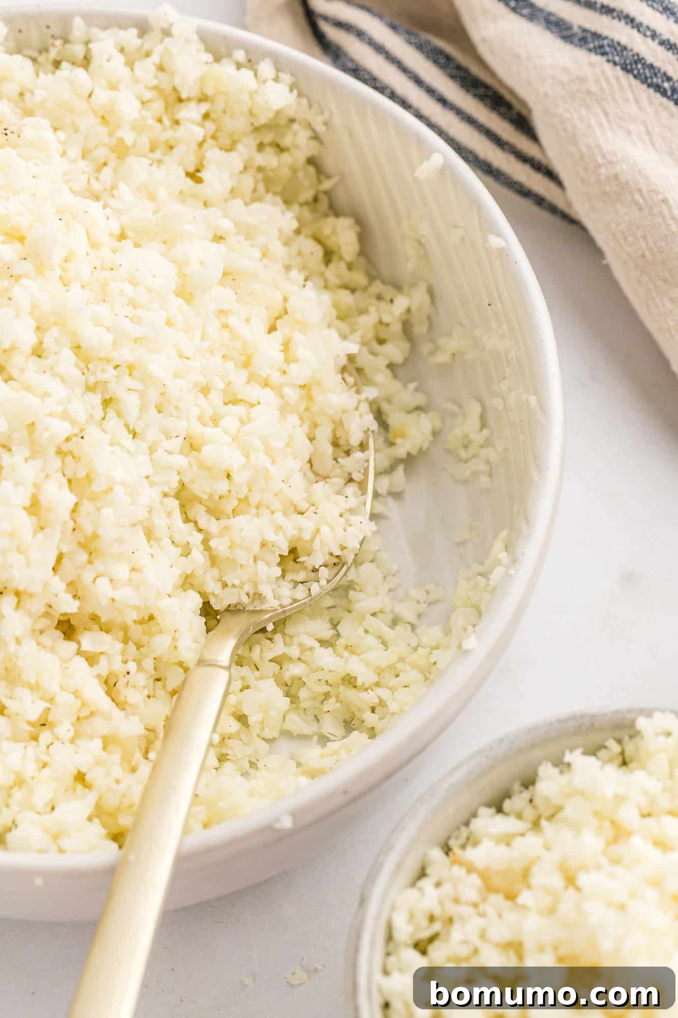 Cauliflower rice in a serving bowl with a spoon, ready to be enjoyed as a healthy, low-carb side dish.