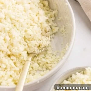 Cauliflower rice in a bowl with a serving spoon.