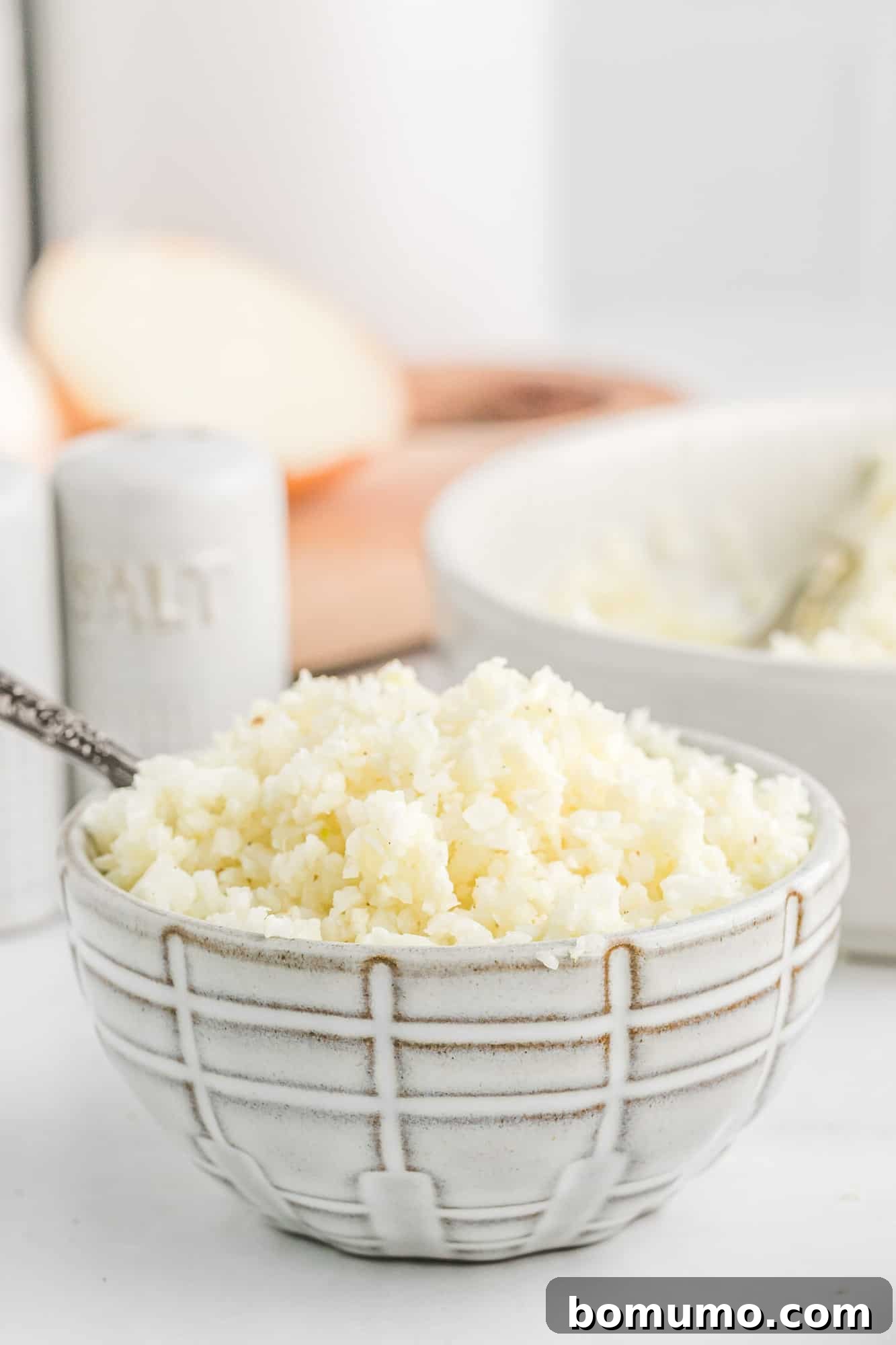 Freshly riced cauliflower in a small black and white bowl, showcasing its fine, grain-like texture.