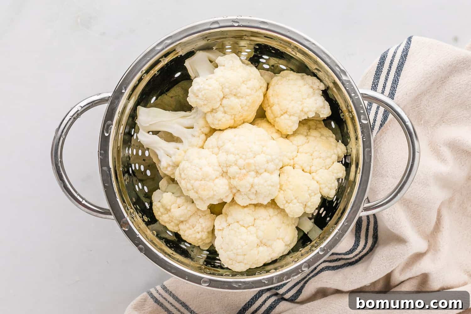 Clean cauliflower florets neatly arranged in a colander after washing, ready for the next step of ricing.