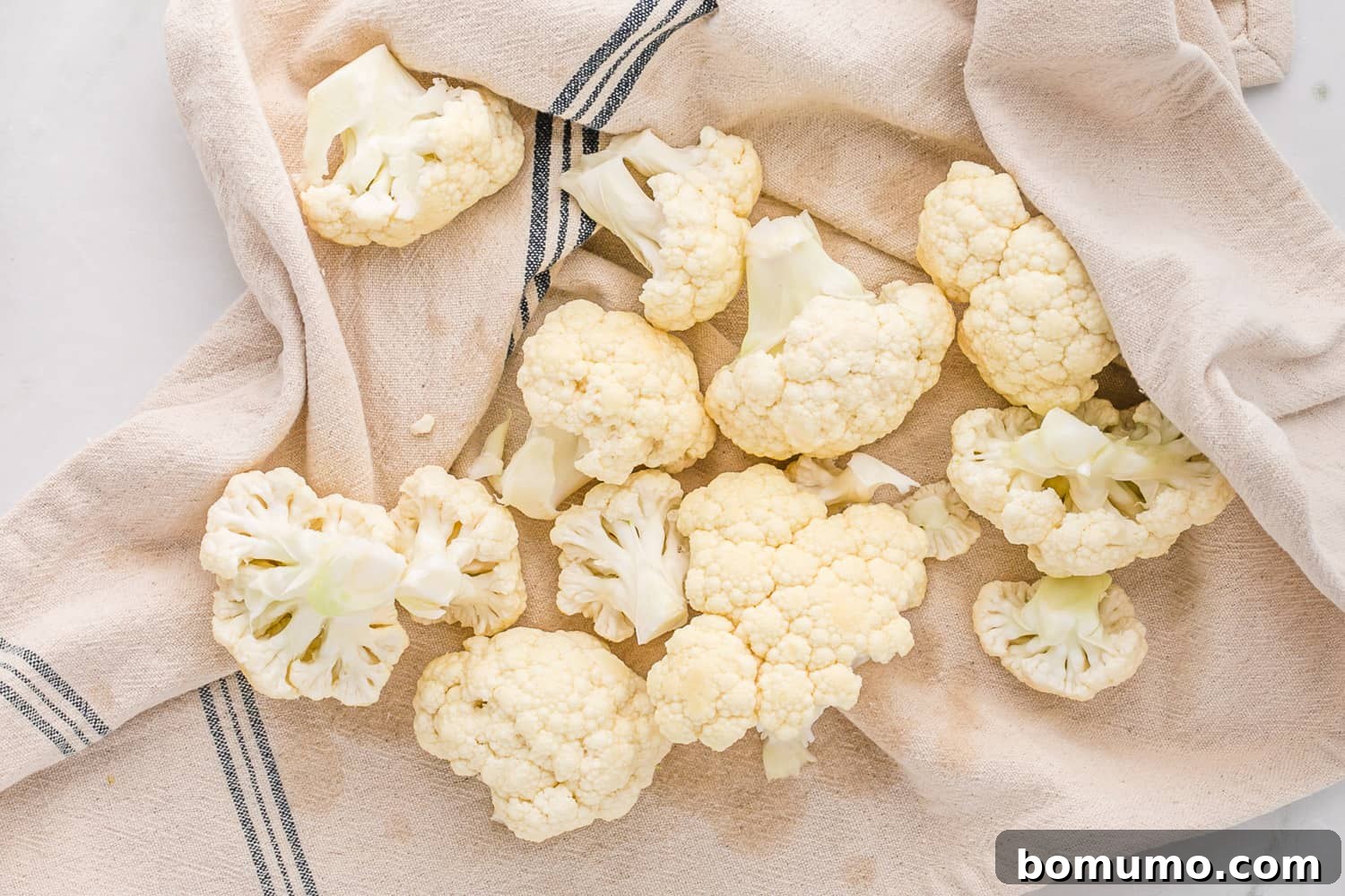 Cauliflower florets wrapped in a kitchen towel to remove excess moisture before processing, a crucial step for perfect cauliflower rice.
