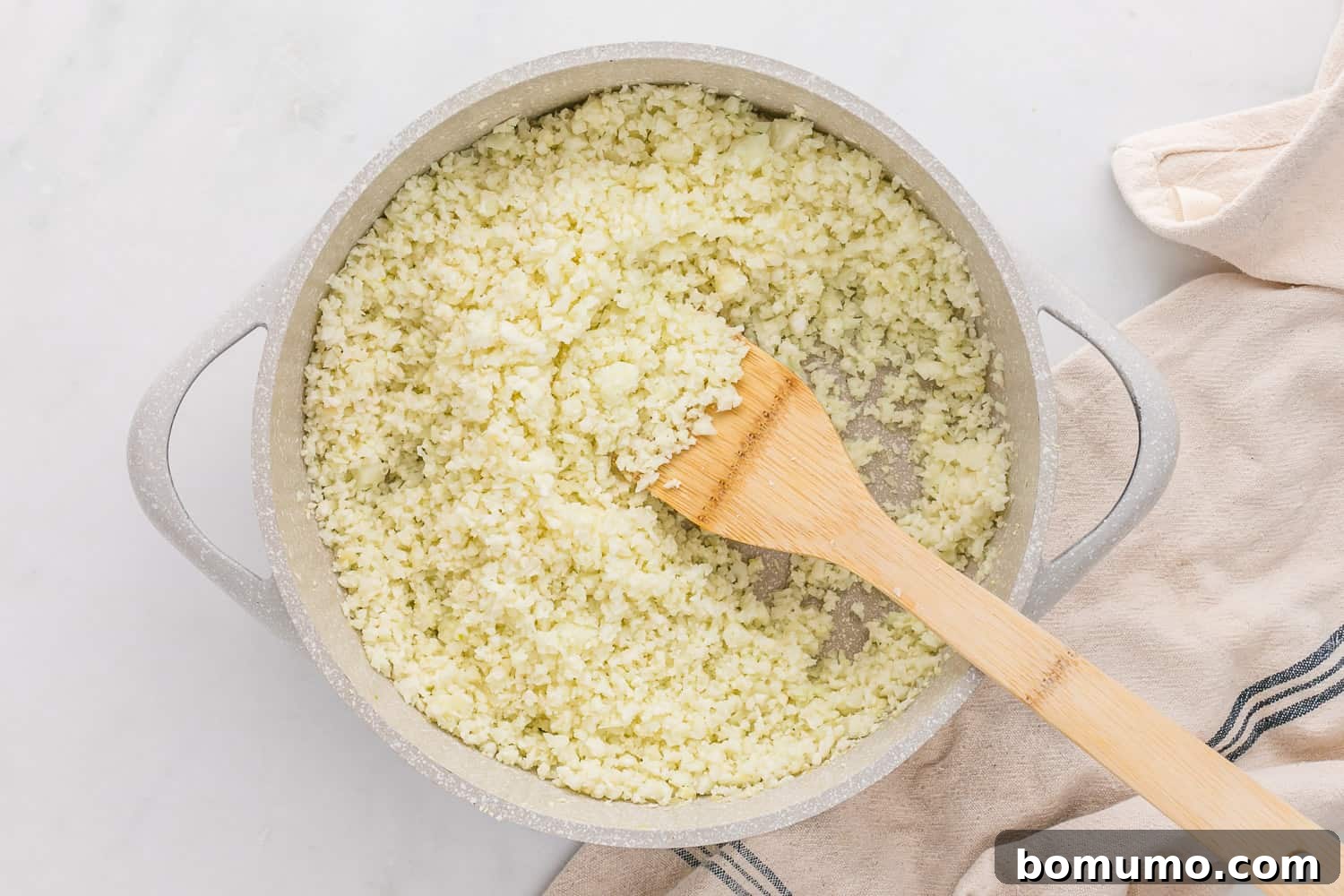 Perfectly cooked cauliflower rice, light and fluffy, resting in a white skillet after being seasoned and ready for serving.