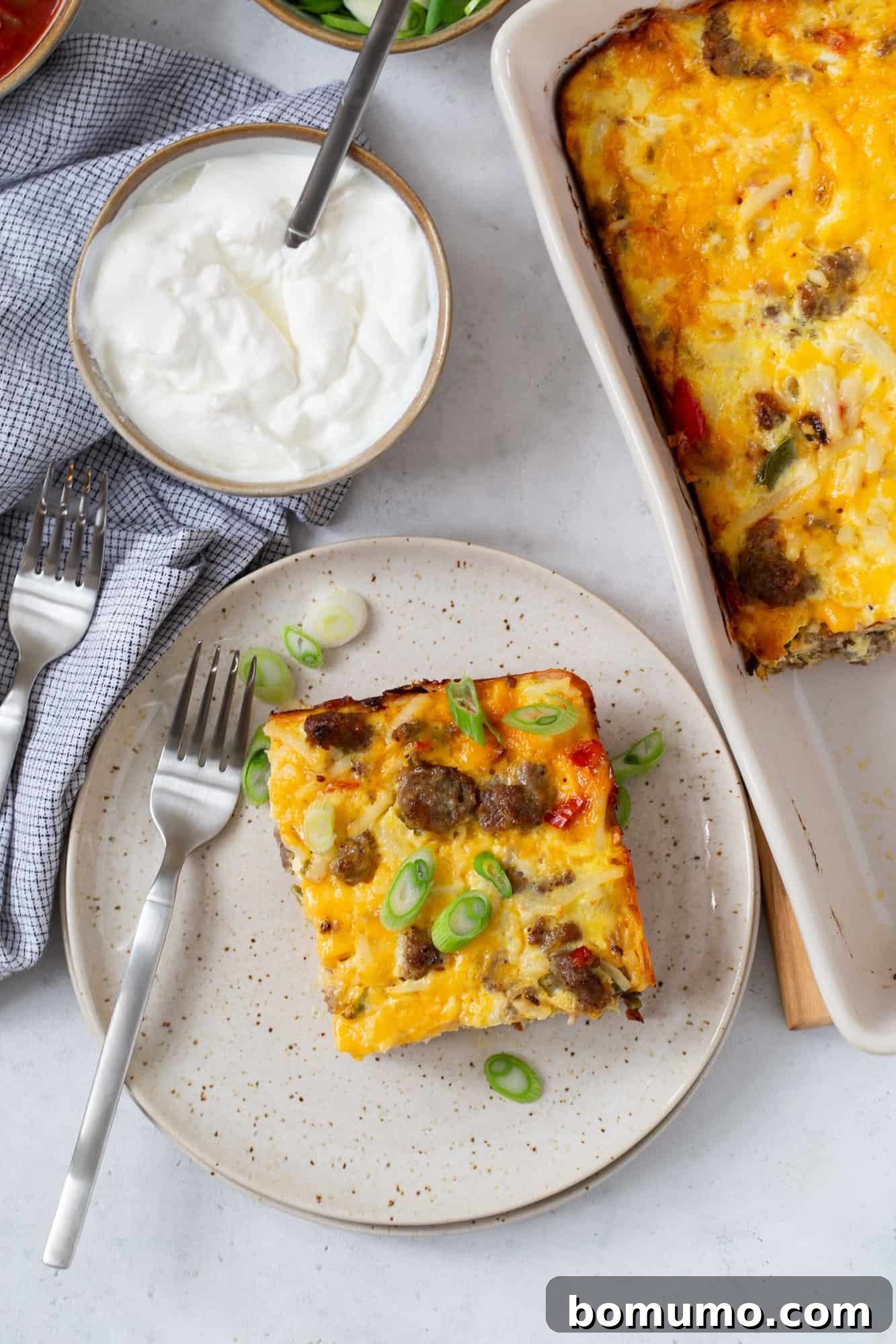 Overhead view of slice of breakfast casserole topped with sliced green onions.