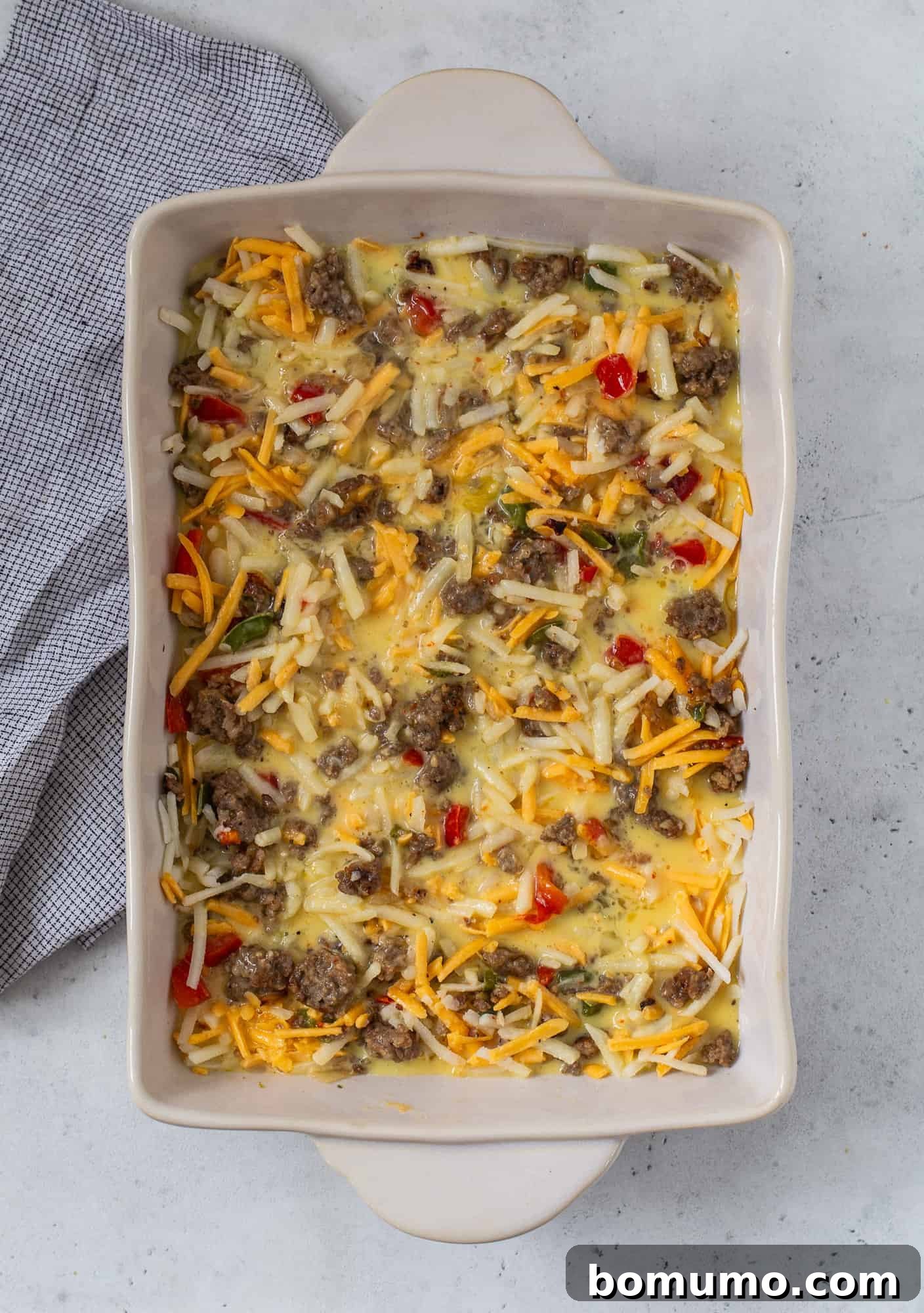 Egg mixture added to hash browns, sausage, vegetables.