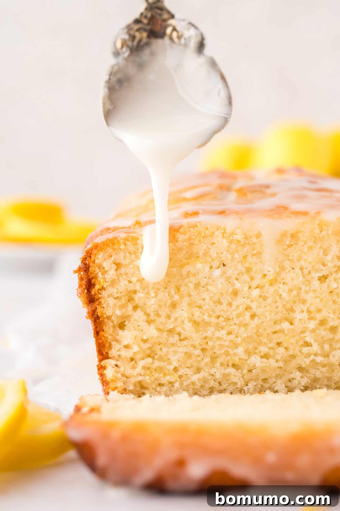 Glaze being drizzled on a cut loaf of lemon bread.