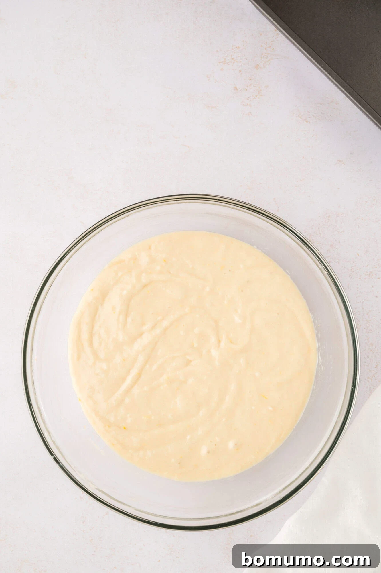 Completed lemon bread batter in a clear glass mixing bowl.