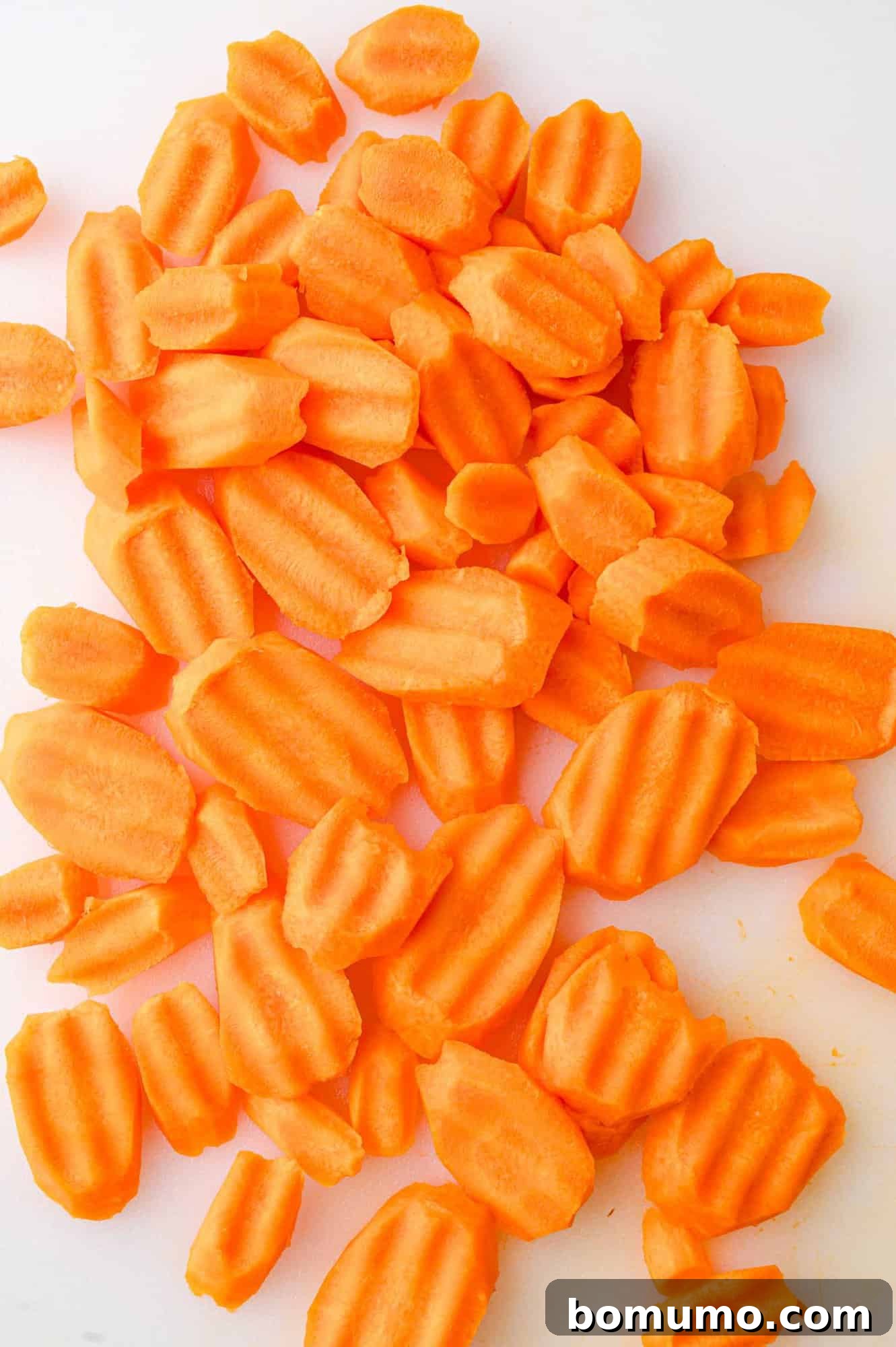 Crinkle-cut carrot slices neatly arranged on a cutting board, ready for seasoning.