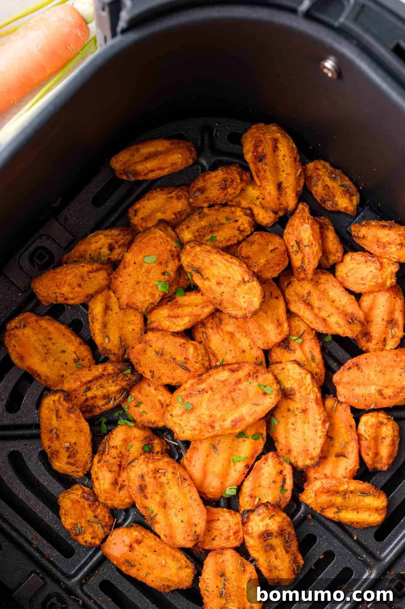 Finished crinkle-cut carrot slices, beautifully cooked, remaining in the air fryer basket.