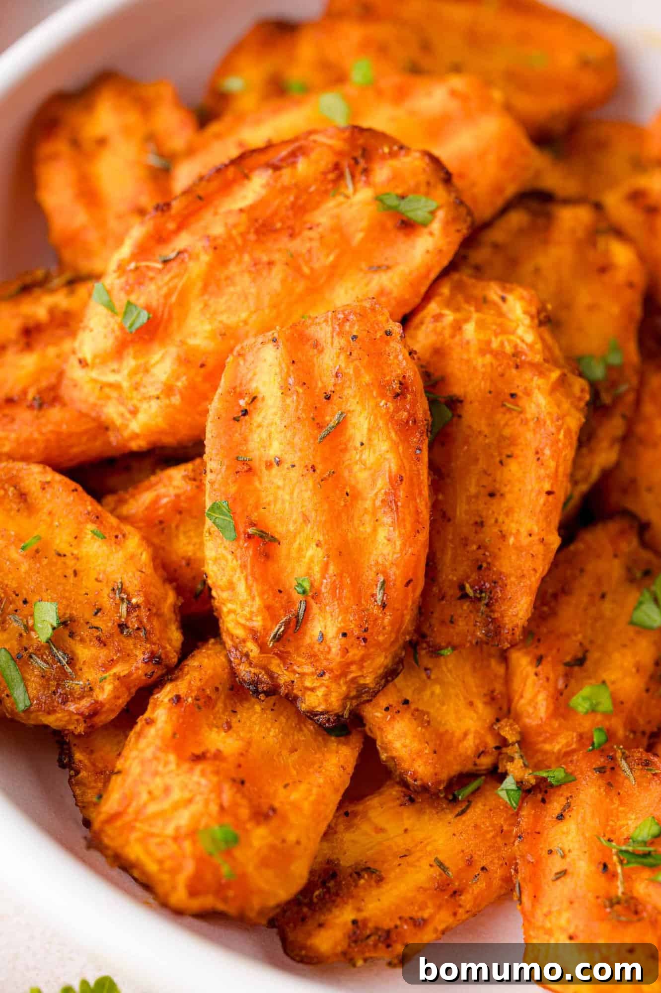 A close-up view of succulent, cooked air fryer carrots, beautifully browned and garnished.