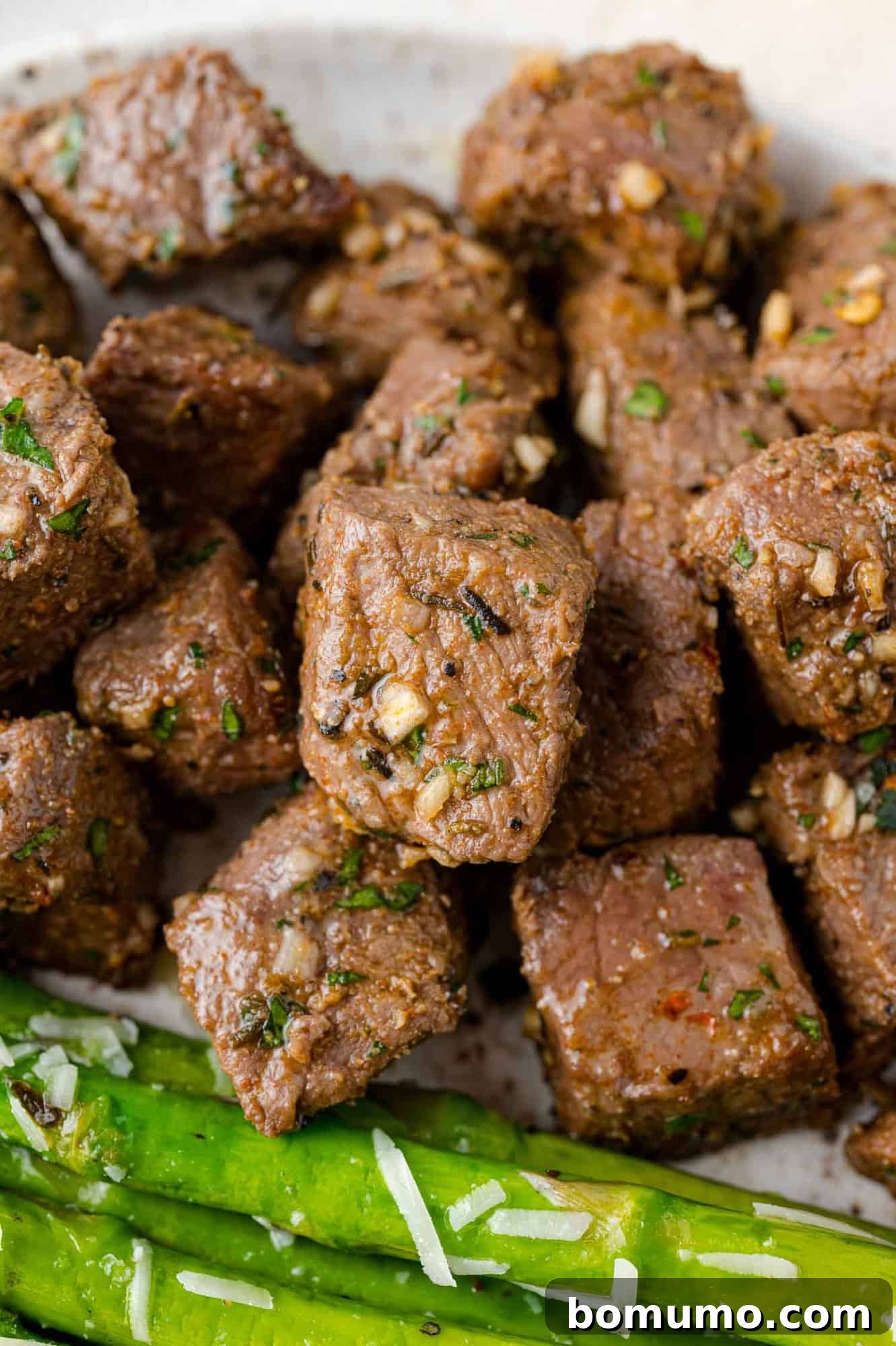 A delicious plate featuring air fryer steak bites next to perfectly sautéed asparagus, garnished for an appealing presentation.