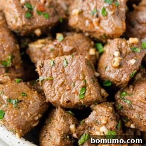 Close up of perfectly cooked air fryer steak bites with garlic parsley butter, ready to be enjoyed.
