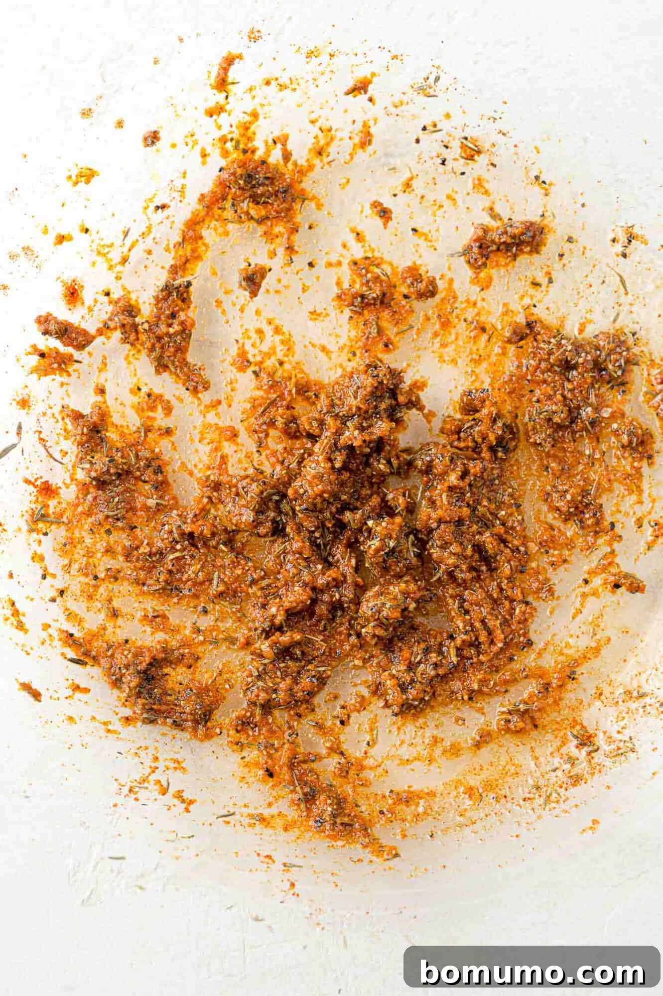 A glistening marinade, a mixture of olive oil, Worcestershire sauce, Dijon, and spices, resting in a clear glass bowl.