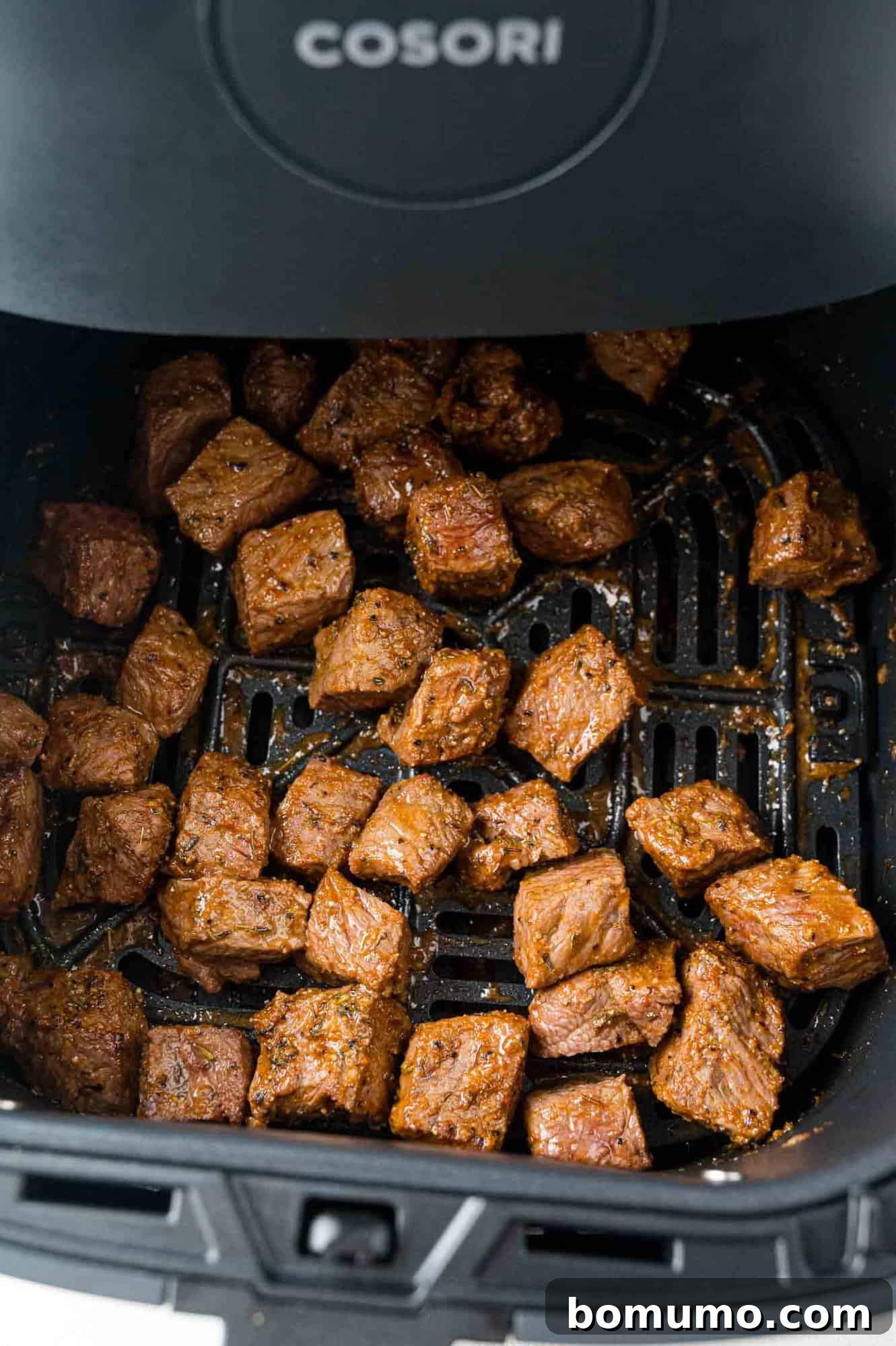 Perfectly cooked and seared steak bites, still hot in the air fryer basket, demonstrating ideal browning and tenderness.