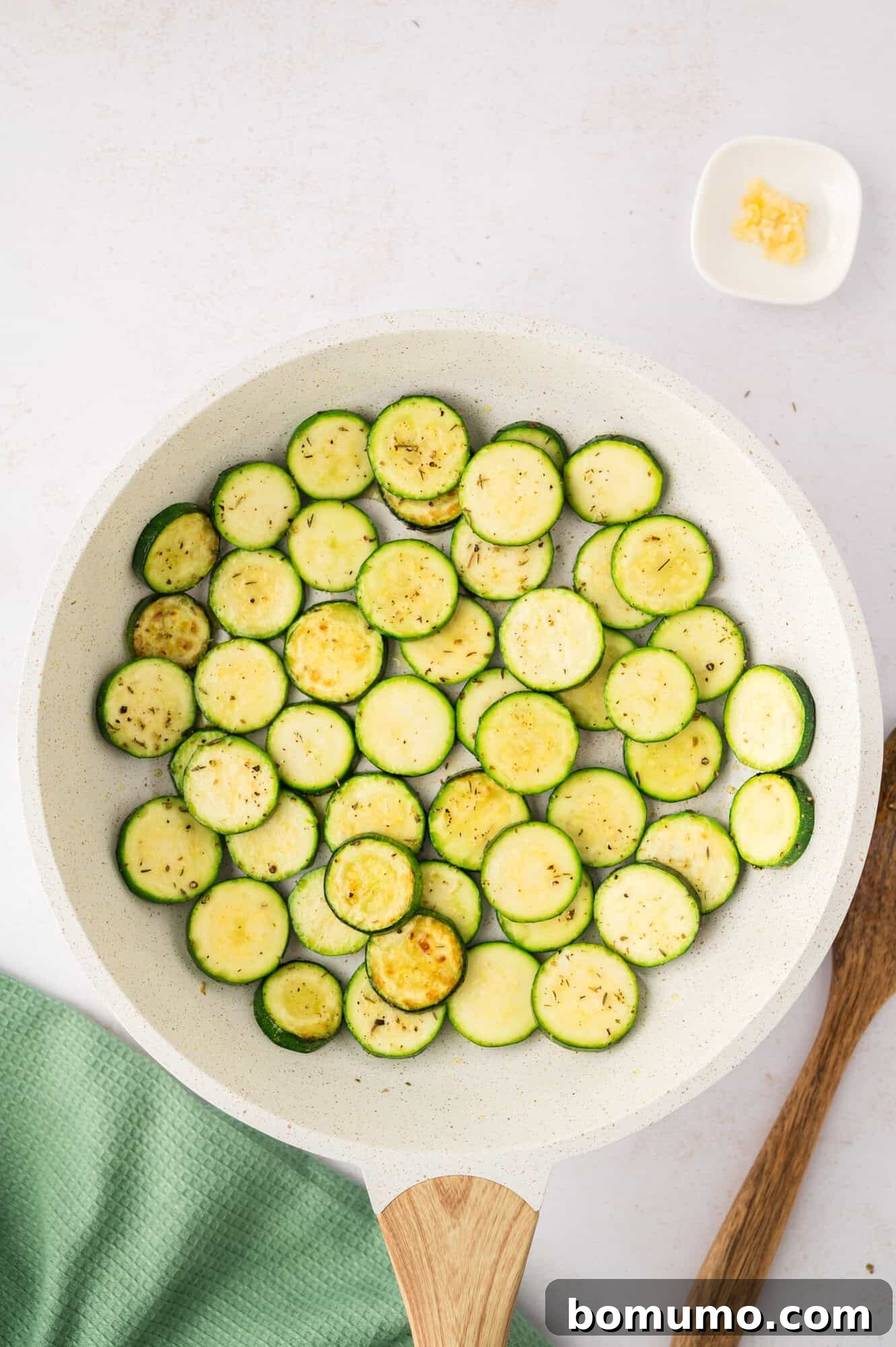 Partially sautéed zucchini slices, beginning to brown and tenderize.